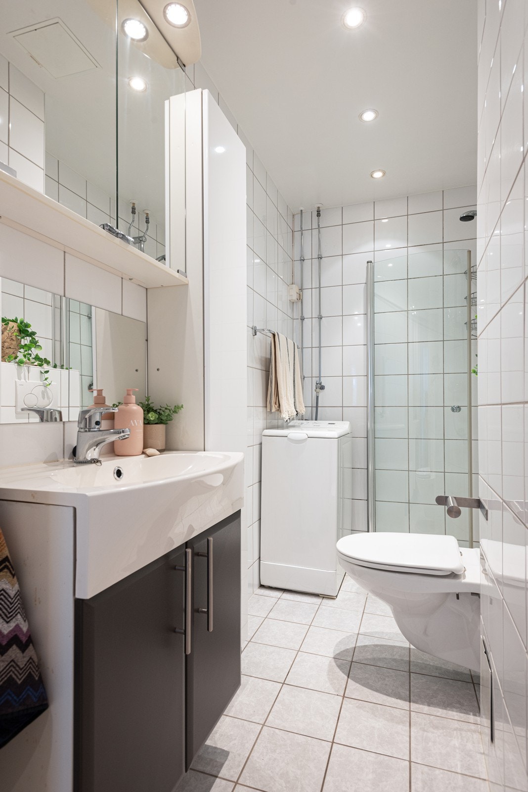 Badet er utstyrt med dusjhjørne, innfellbare dusjdører, veggmontert wc, servantskap, naturlig avtrekk og stoppekran Galleribilde