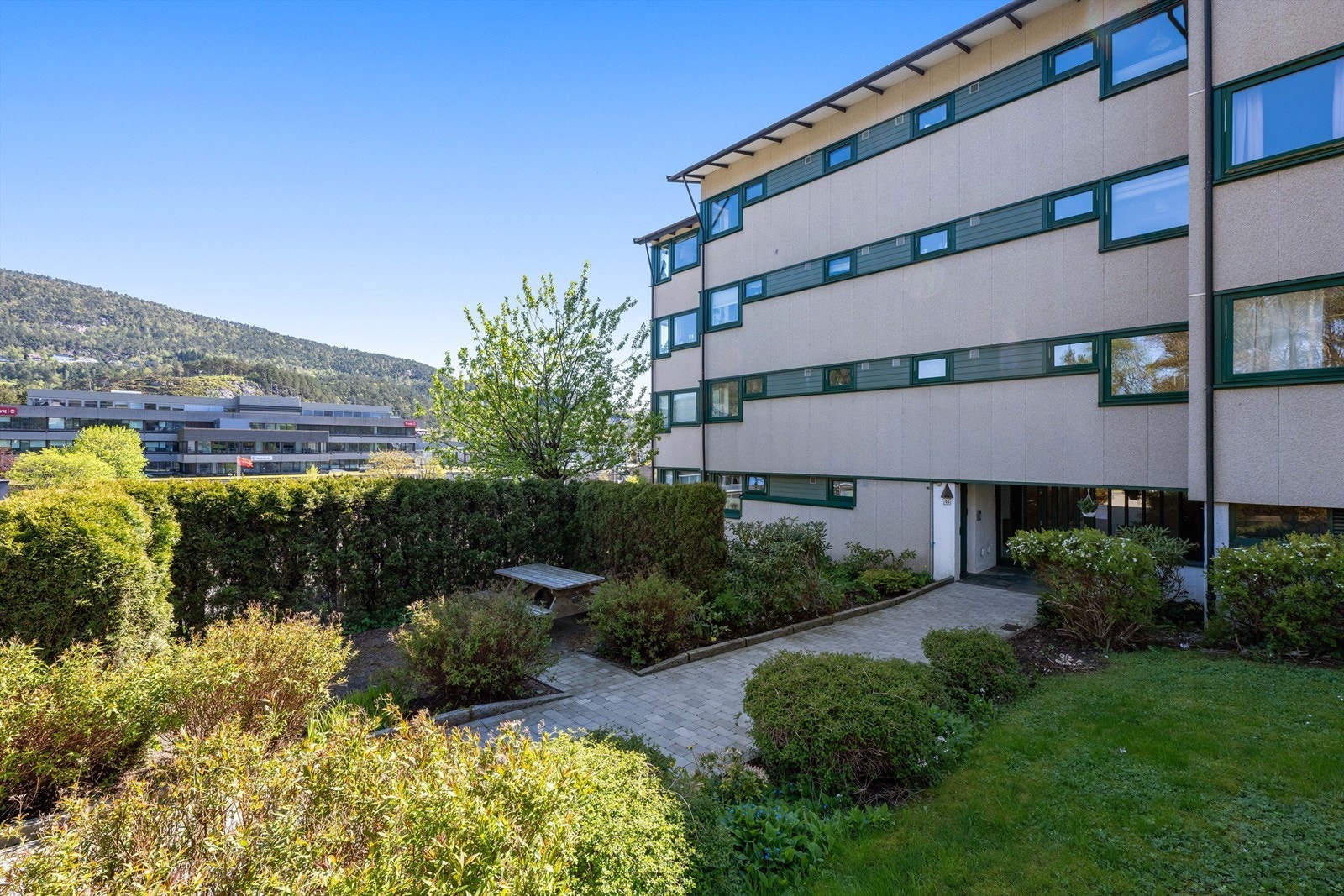 Inngangspartiet til bygningen er pent opparbeidet med belegningsstein og grønne arealer. Galleribilde