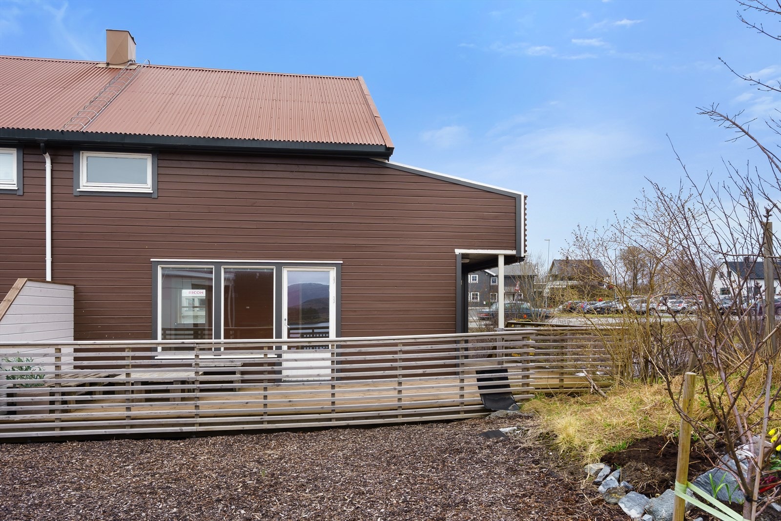 Felles tomt for borettslaget, varierte overflater, asfalt, grus, kratt, fjell og bratt skråning mot sjø. Galleribilde