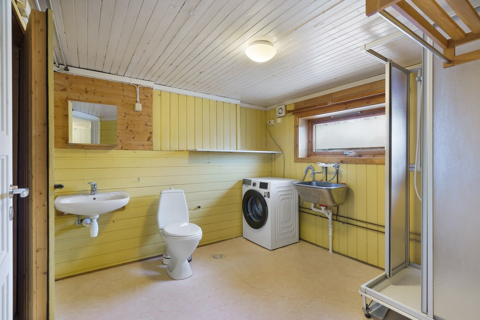 På badet/vaskerom er det opplegg for vaskemaskin, montert et toalett, en vask på vegg og et skyllekar på vegg. Galleribilde