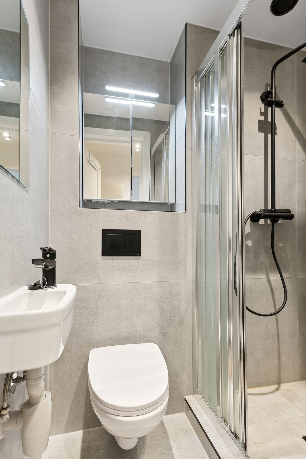 Nydelig flislagt bad med egen dusjsone, wc, servant og flere overskap med speil og oppbevaring. Galleribilde