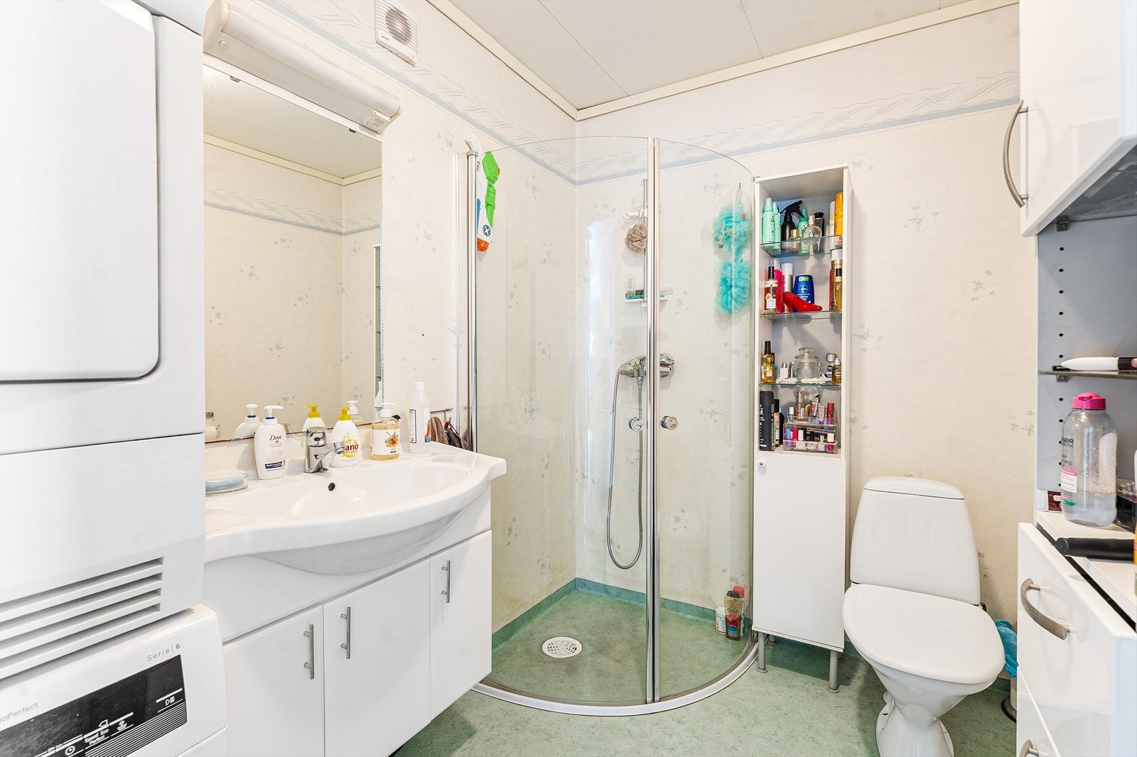 Badet er innredet med servant med underskap, toalett, dusjhjørne og opplegg for vaskemaskin Galleribilde