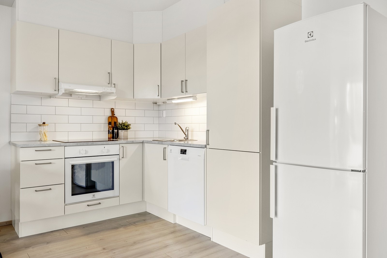 Innredningen består av kremhvite, slette fronter, laminat benkeplate og håndtak i aluminium. Galleribilde