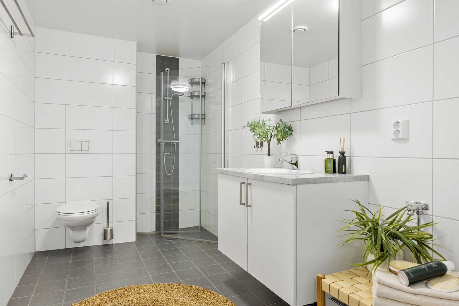 Badet er utstyrt med vegghengt toalett, servant med skap og dusjnisje med innfellbare glassdører. Galleribilde