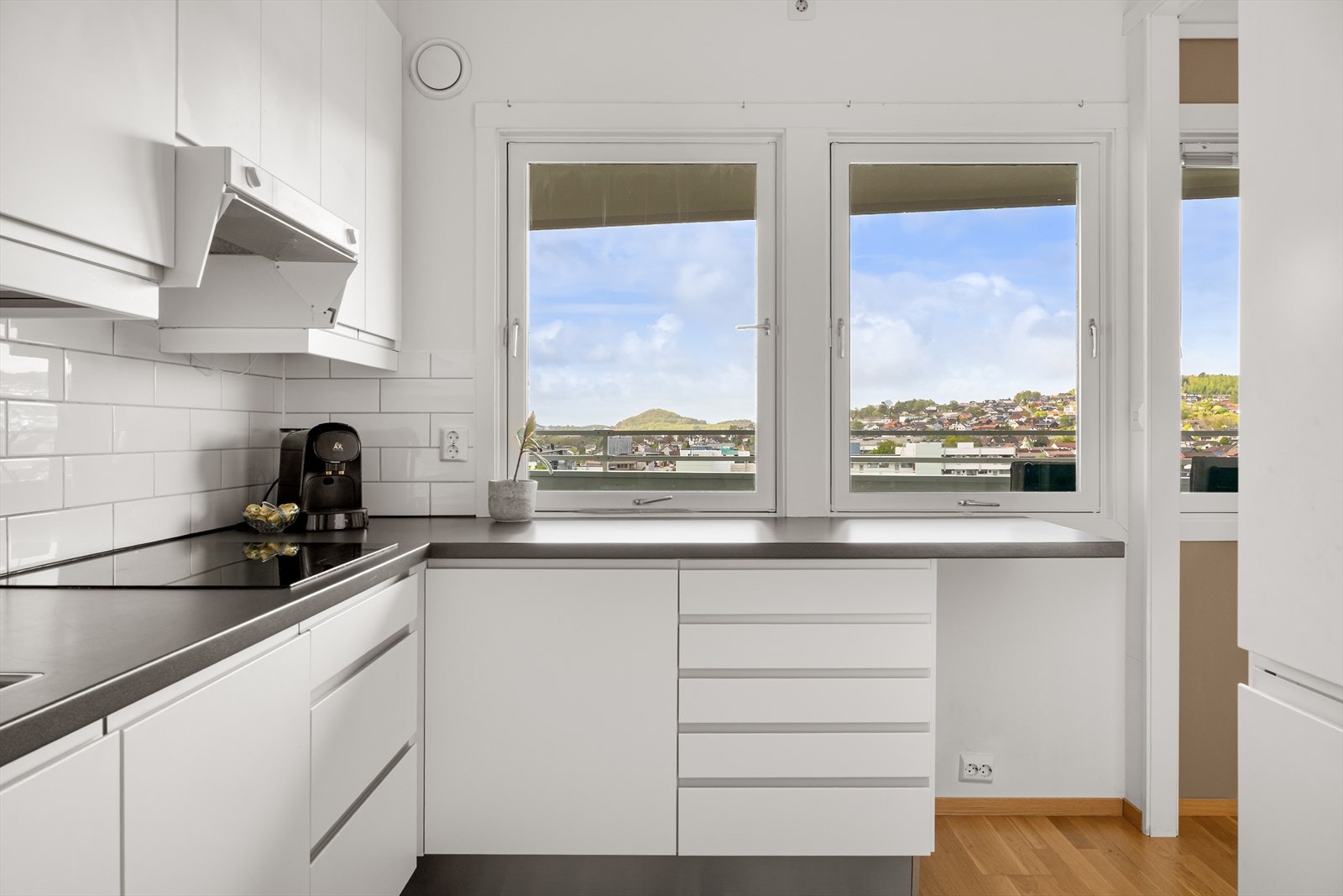 Kjøkkenet fremstår moderne og stilrent, med hvite, glatte fronter og benkeplate av laminat som gir et tidløst uttrykk. Galleribilde