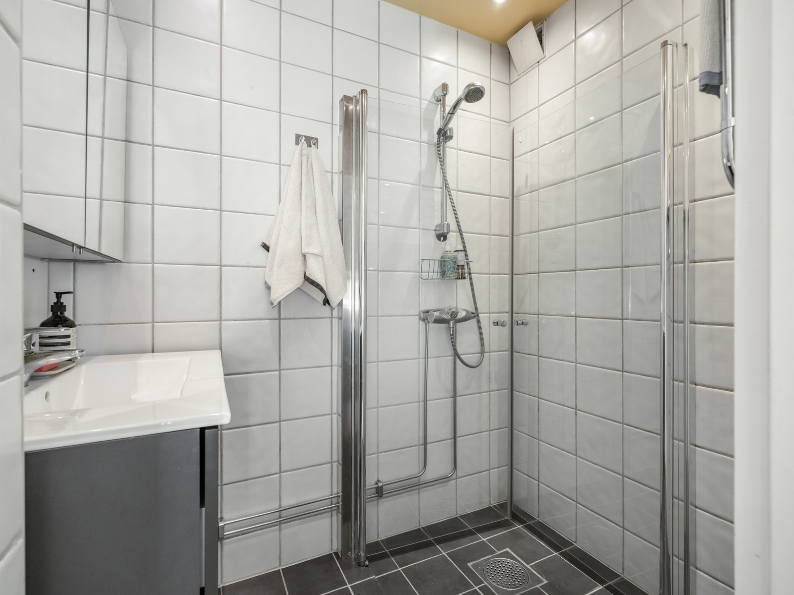 Badet er innredet med dusjhjørne, servant med praktisk skuffinnredning og speilskap. Det er varme i gulvet og downlights i himling. Galleribilde