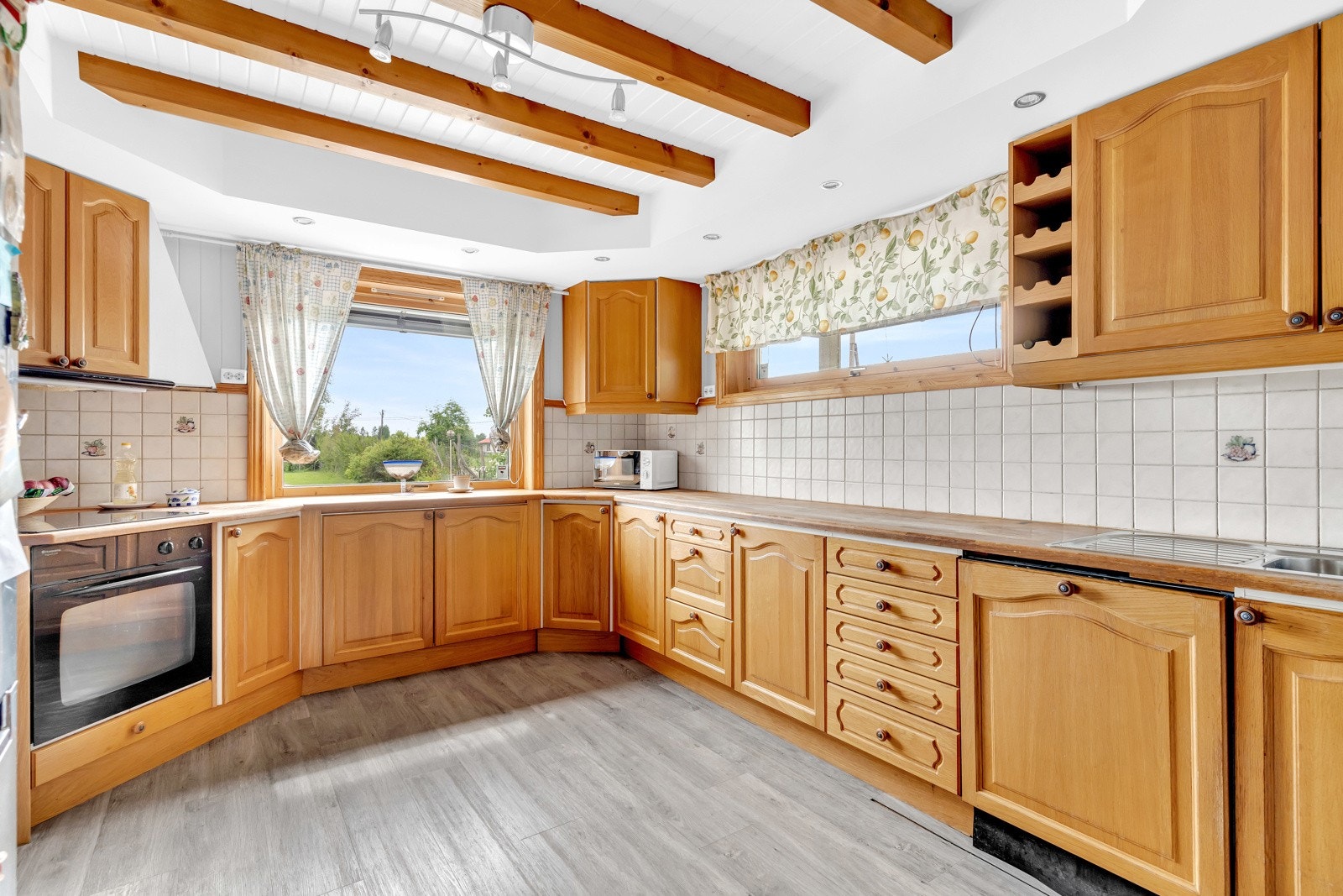 Kjøkkeninnredningen har profilerte fronter og fliser mellom benkeplate og overskap. Det er godt med skap- og benkeplass på kjøkkenet. Galleribilde