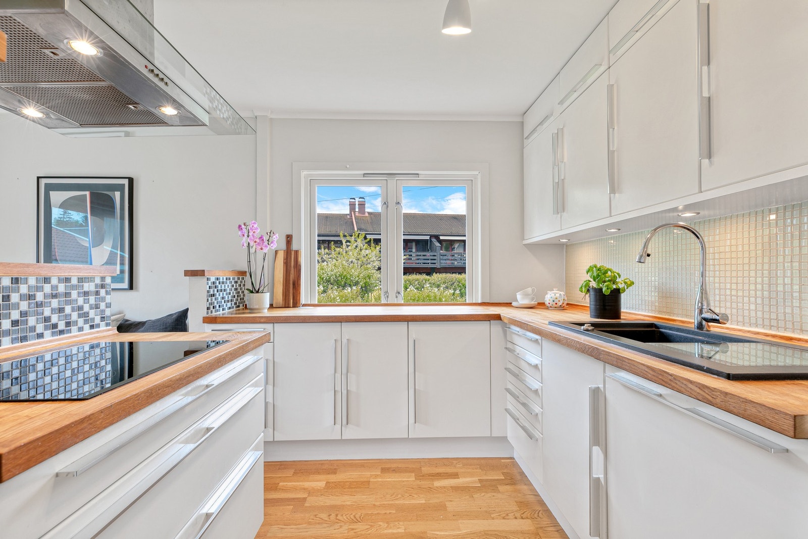 Innredningen har glatte fronter, benkeplater i behandlet tre og en nedfelt kum av kompositt. Fliser over benkeplate Galleribilde