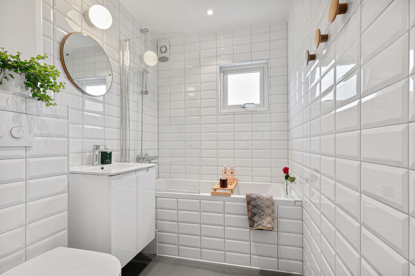 Bad fra 2017 innredet med vegghengt toalett, nedfelt servant med skap og et innfliset badekar med glassvegg Galleribilde