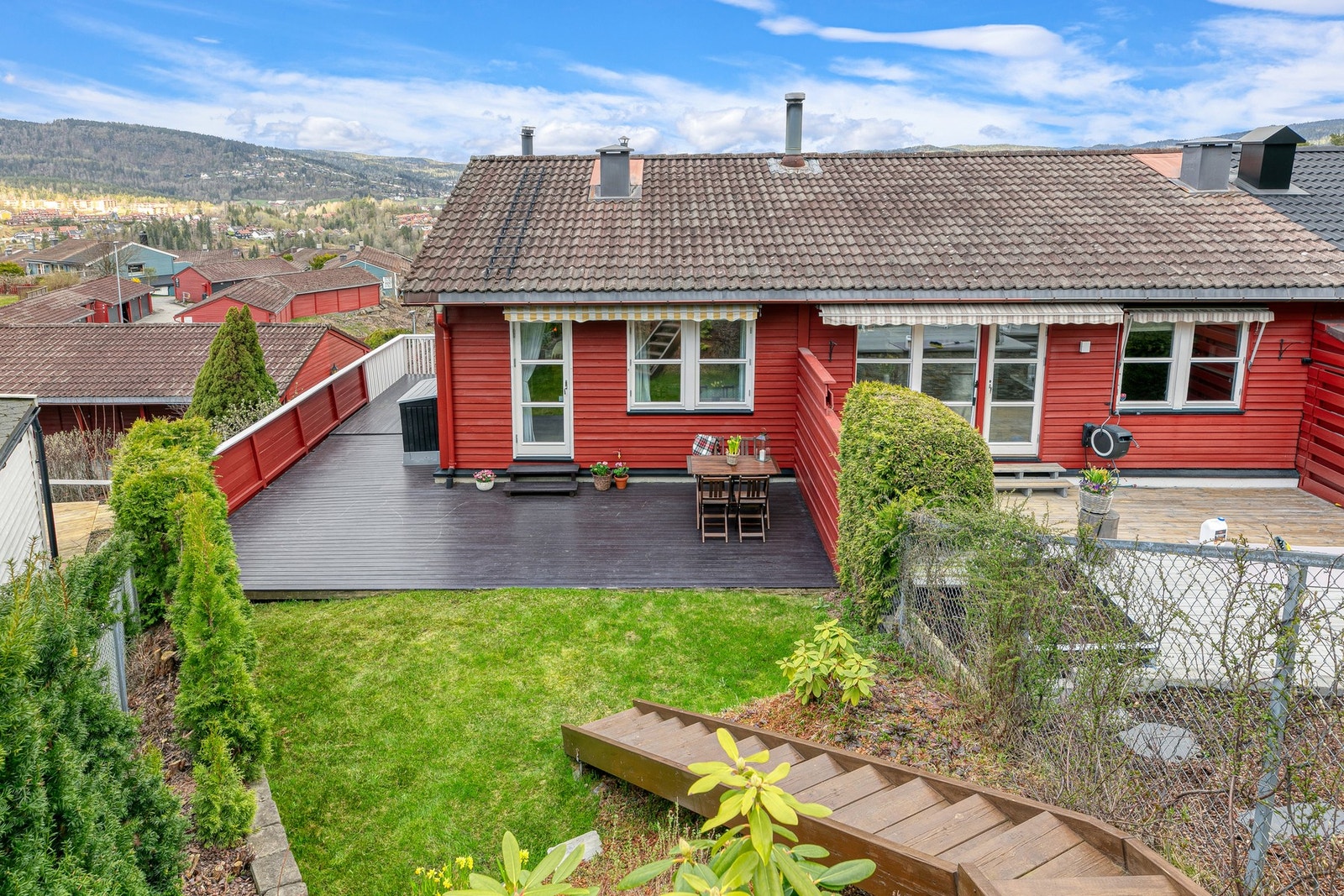 Utenfor terrassen er opparbeidet en hyggelig hage med plen og diverse busker Galleribilde