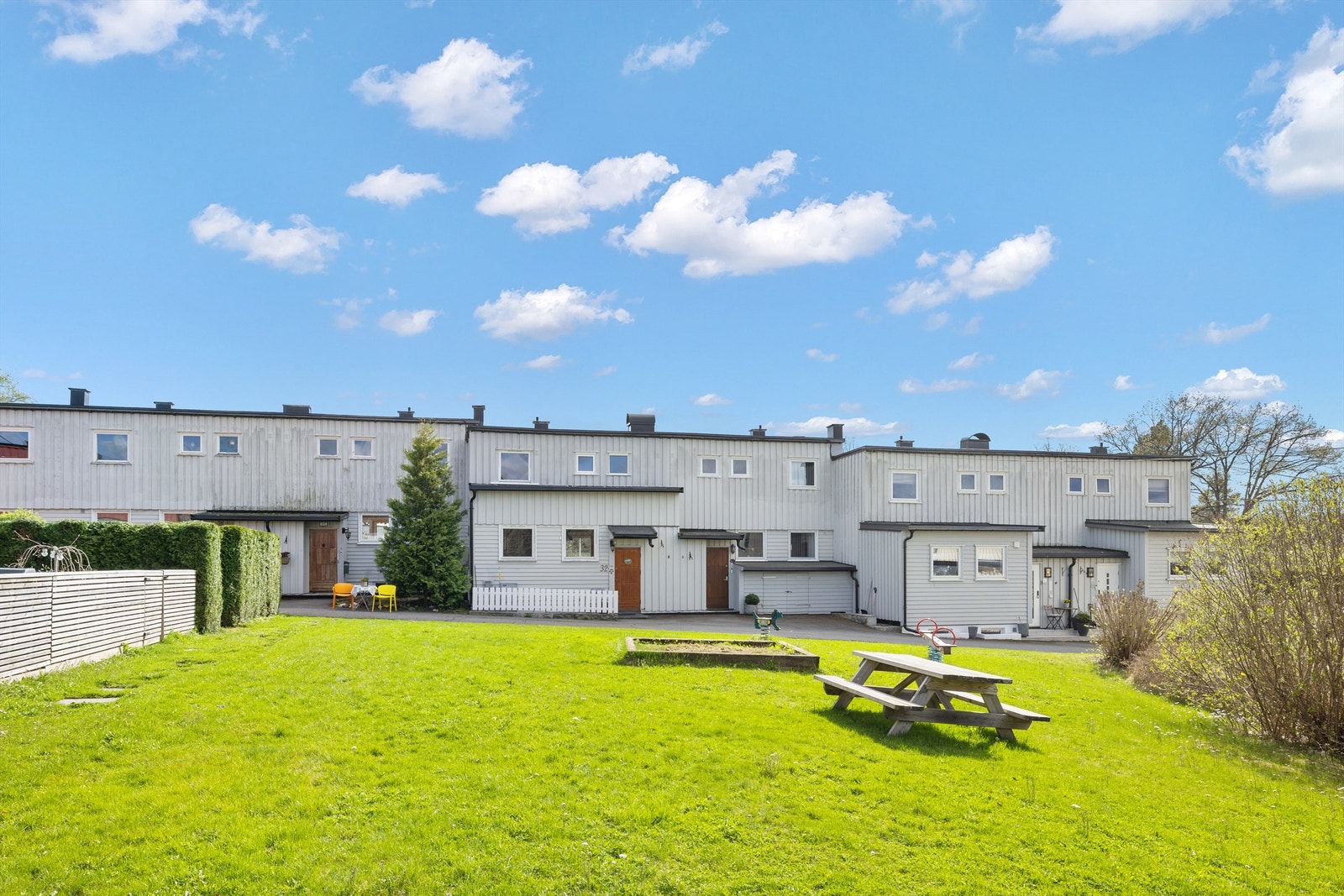 På nordsiden av rekkehuset er det et felles tun med prydbusker, lekeapparater, bord og benker, samt rikelig med boltreplass på den store gressplenen. Galleribilde