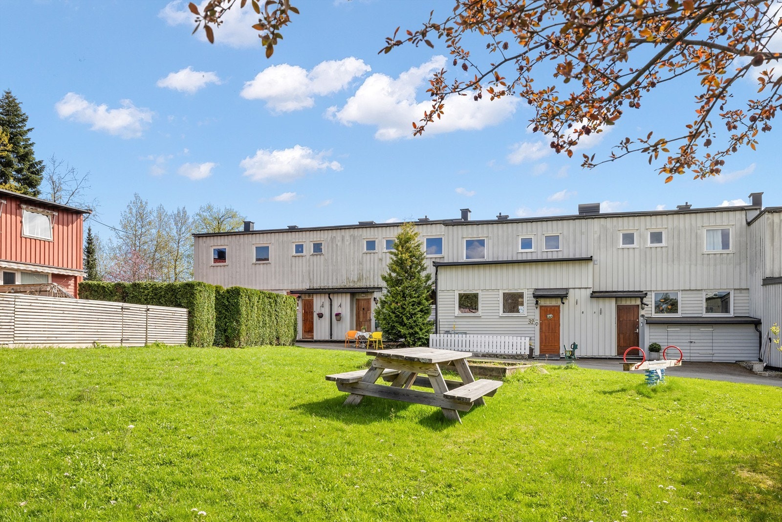 På nordsiden av rekkehuset er det et felles tun med prydbusker, lekeapparater, bord og benker, samt rikelig med boltreplass på den store gressplenen. Galleribilde
