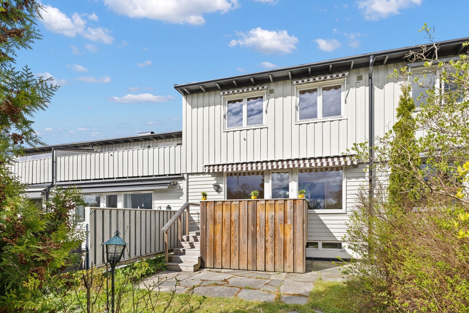 Her er det en skiferbelagt markterrasse, levegger på sidene, flere prydbusker og noen stauder som rammer inn utearealet. Galleribilde