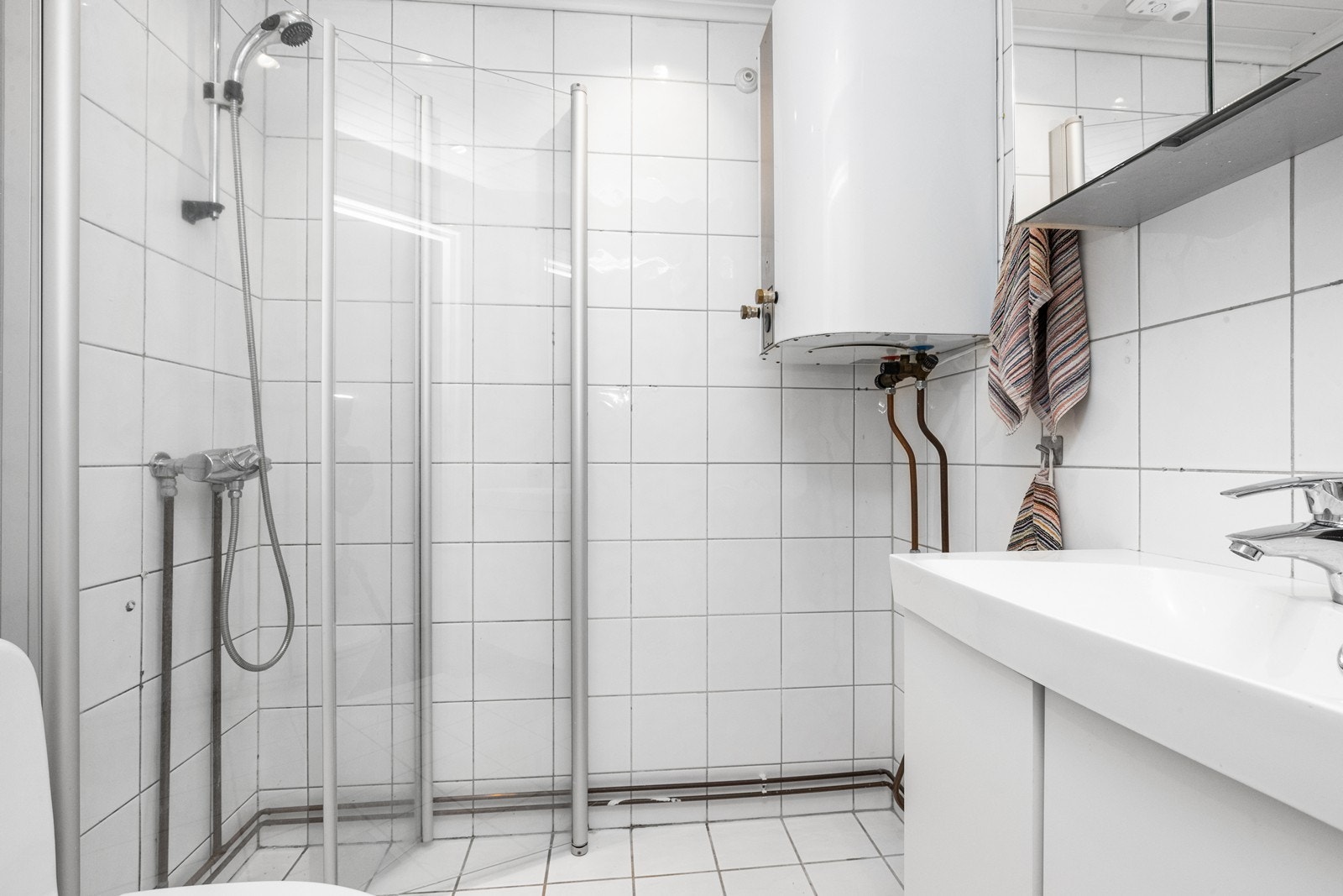 Bad innredet med dusjhjørne, toalett, servantskap med servant og speilskap Galleribilde