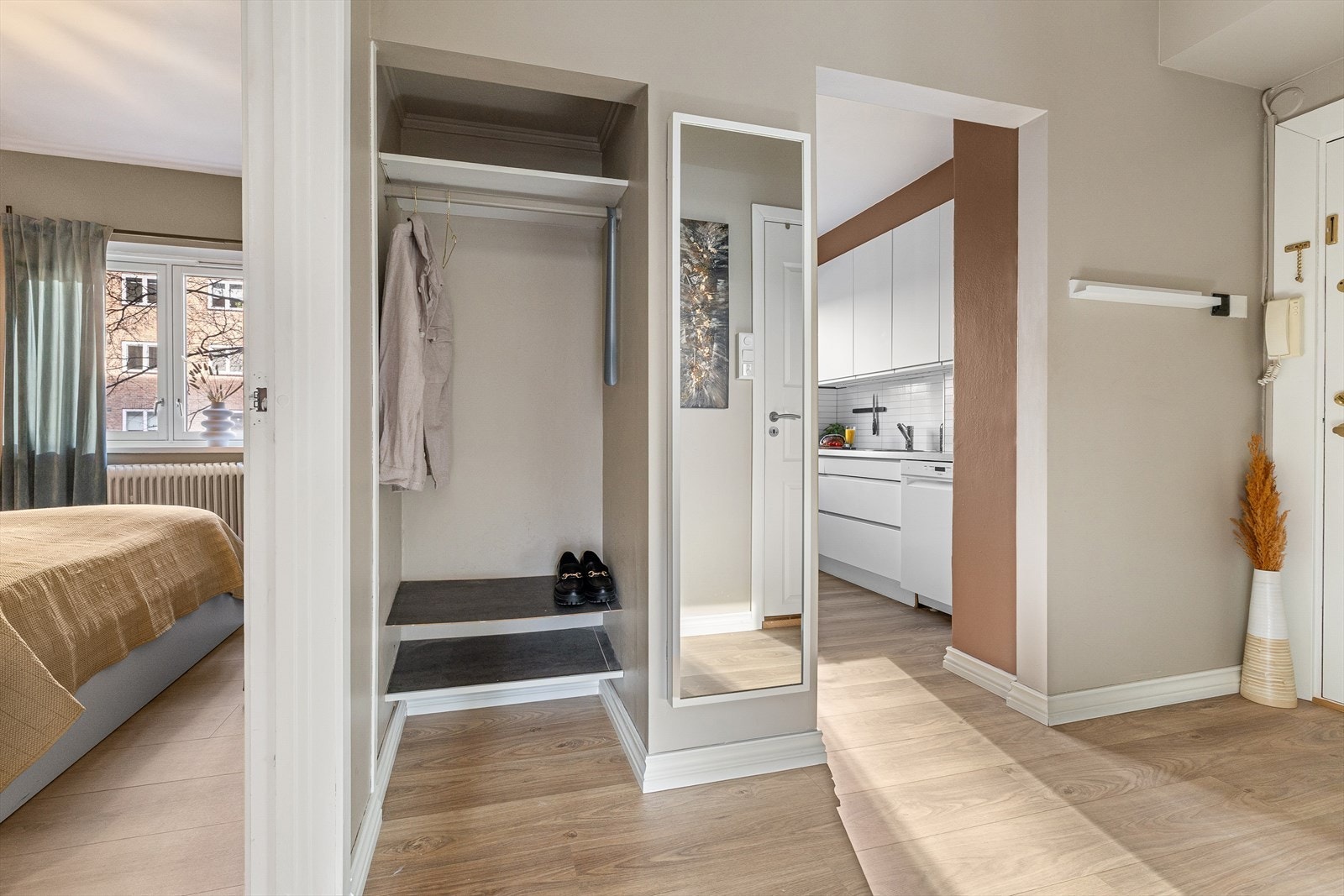 Entré med god takhøyde, laminatgulv og malte veggoverflater. Praktisk nisje med hyller og oppheng for yttertøy Galleribilde