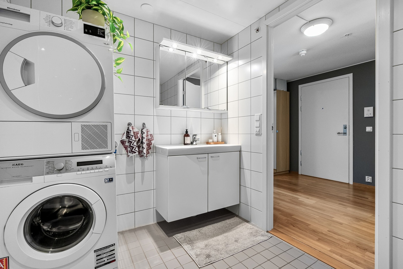 Baderomsinnredningen er hvit, med glatte skapfronter og heldekkende servant. Speilskap med belysning er montert på vegg over servanten. Galleribilde