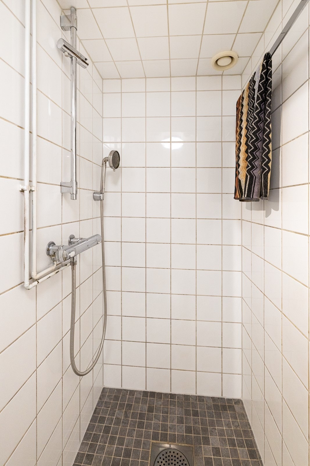 Innredning og garnityr består av gulvstående toalett, dusjplass i nisje med forheng og servant med ettgreps blandebatteri i innredning. Galleribilde