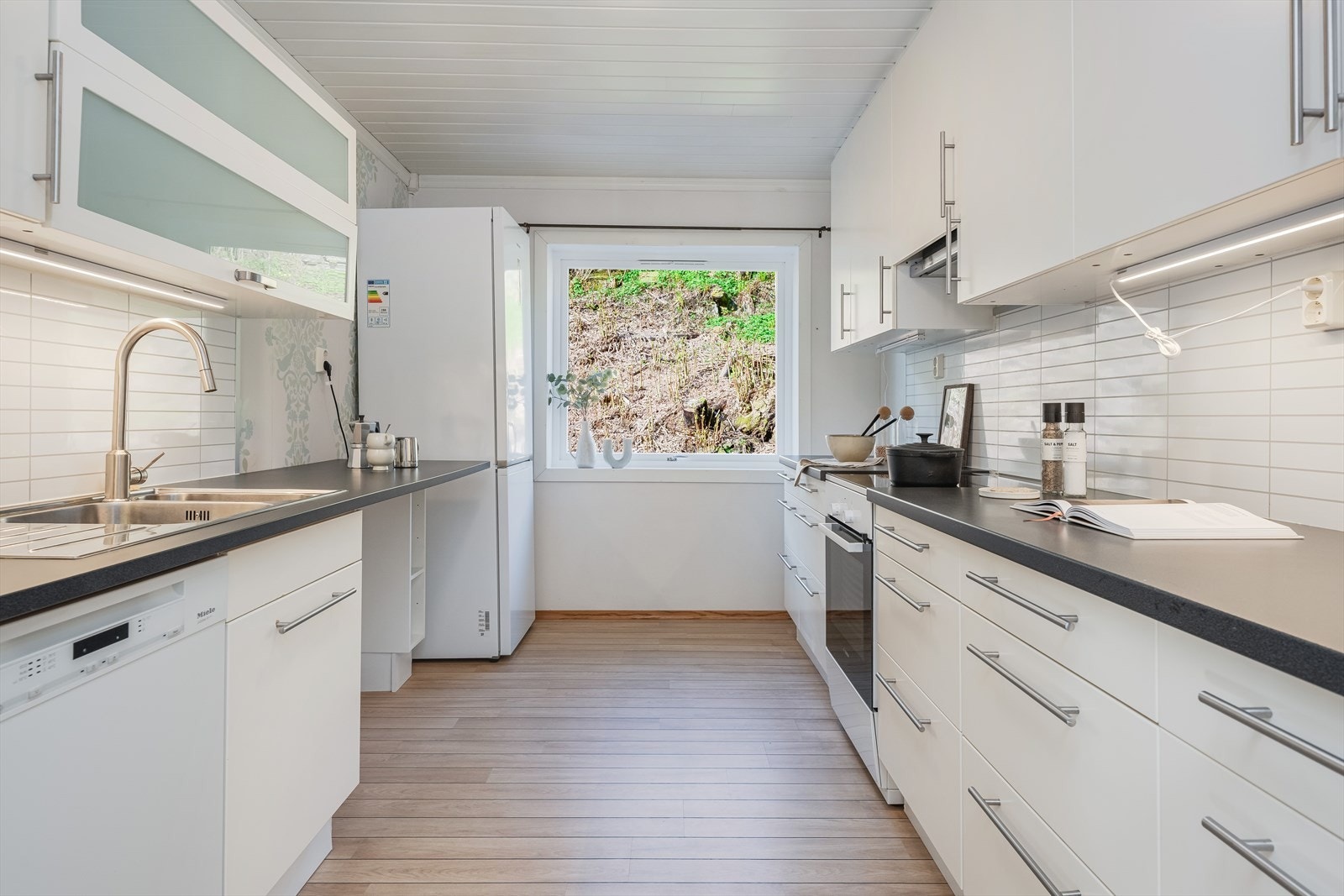 Lyst og moderne kjøkken med rikelig naturlig lys og stilren design. Perfekt for matlaging og sosialt samvær. Galleribilde