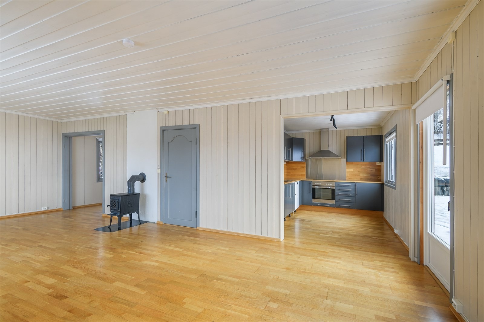 Lyse, men lune overflater i rommet. Stua går i vinkel, med en åpen løsning mot kjøkken. Galleribilde