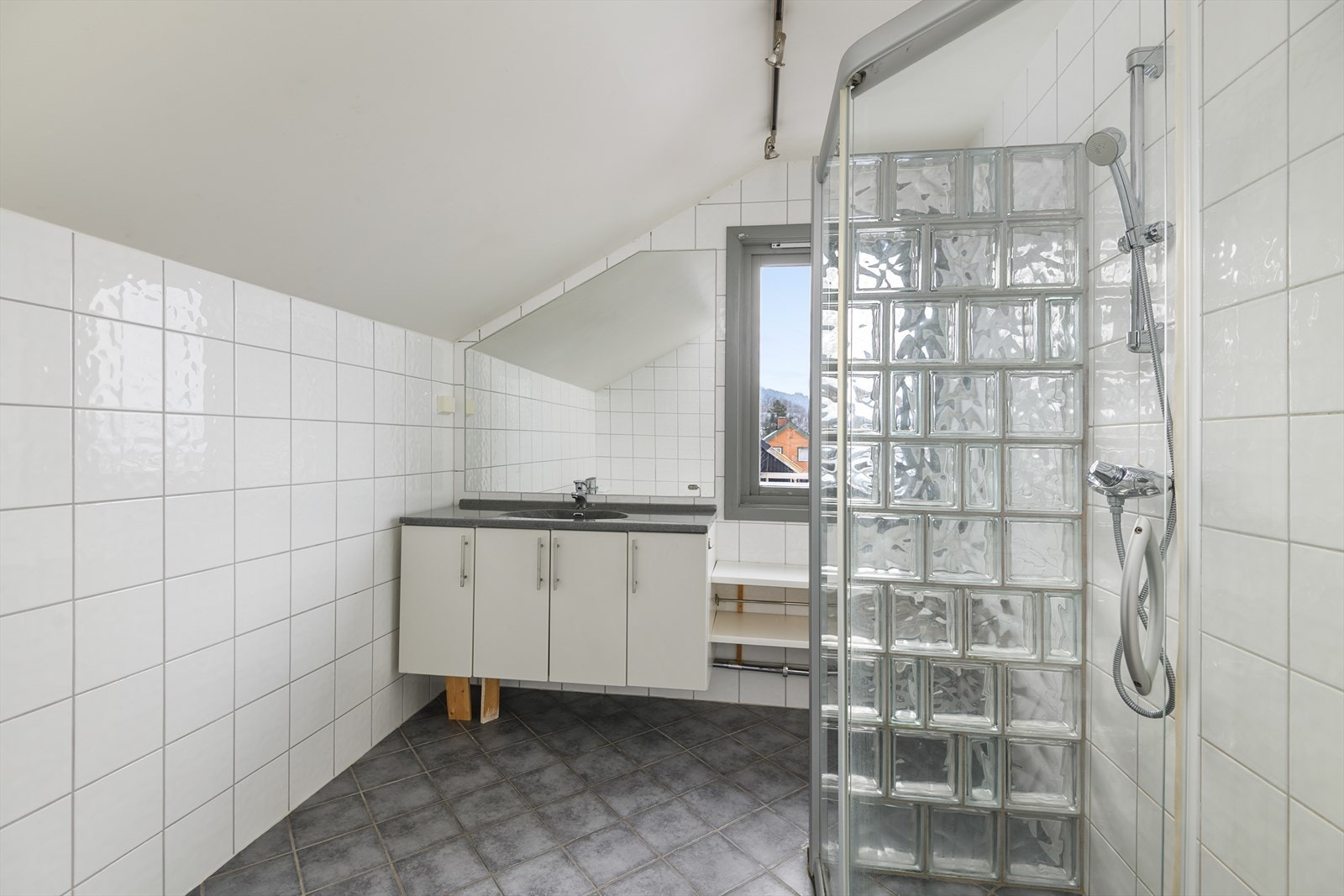 Badet i boligen er plassert i 2. etasje sammen med soverommene. Fliser på gulv og vegger. Servantinnredning, dusj og plass til ekstra kommode. Galleribilde