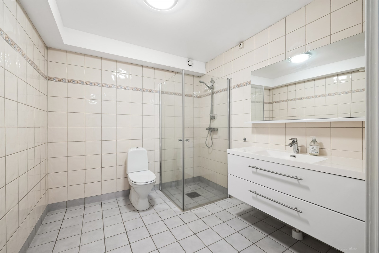 Badet har dusjhjørne med dusjdører av glass Galleribilde