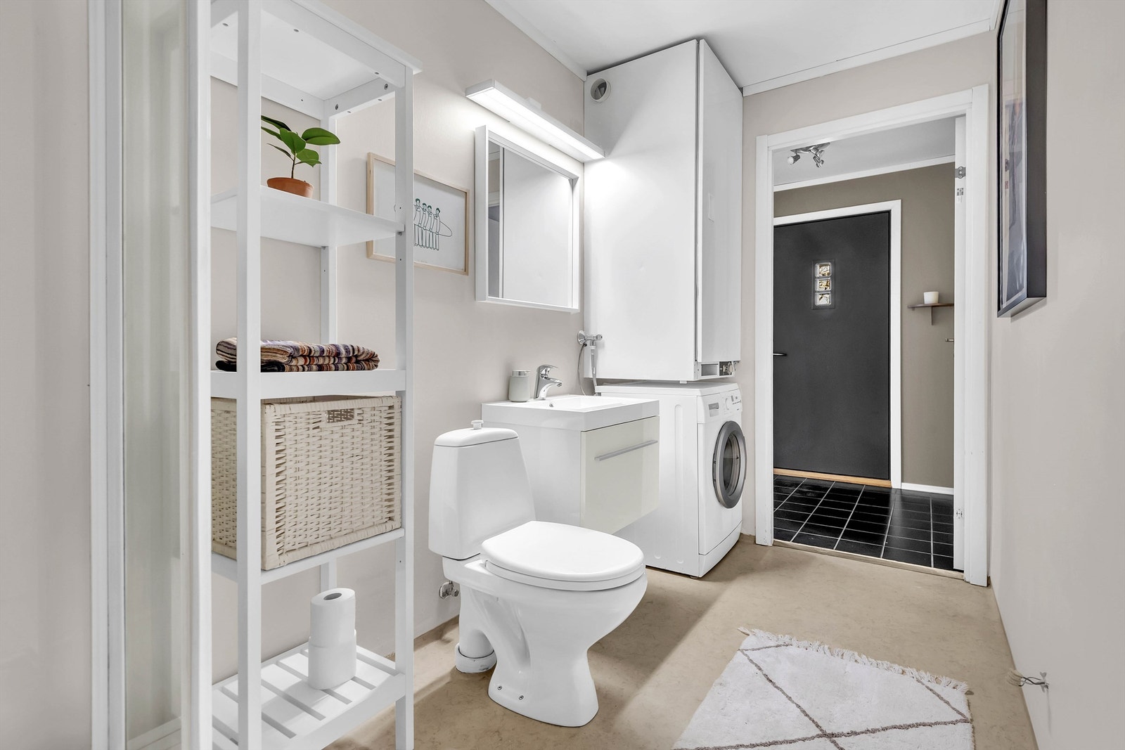 Videre så er det vegghengt tørkeskap over opplegg for vaskemaskin, gulvstående toalett, dusjkabinett i hjørne og innebygget dusjbatteri tilkoblet hånddusj. Galleribilde