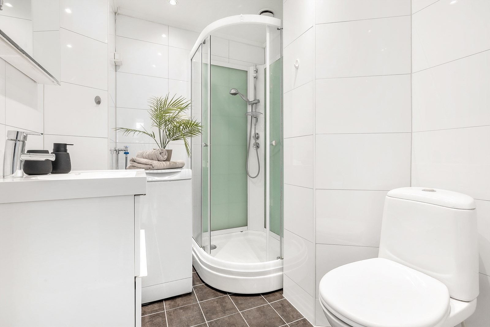 Innredningen er bestående av servant med underskap, overskap med speildør, dusjkabinett med skyvedører, frittstående toalett og opplegg for vaskemaskin Galleribilde