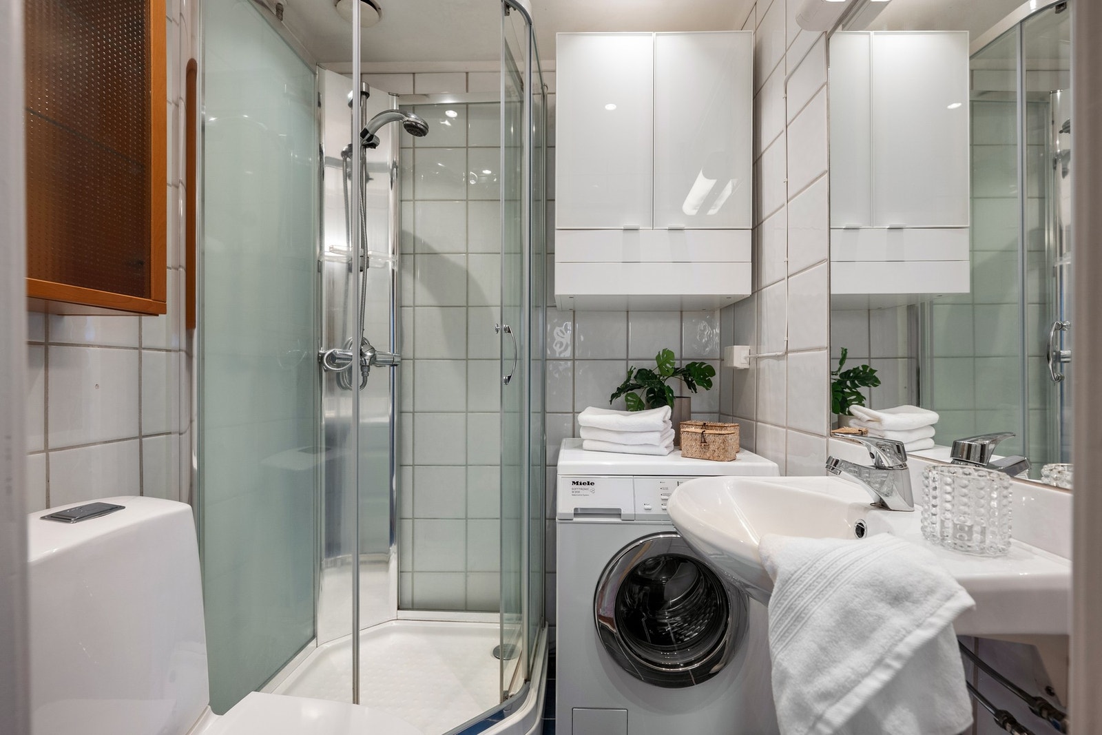 Badet er effektivt utnyttet og er innredet med toalett, dusjkabinett, servant, veggskap samt vaskemaskin. Galleribilde