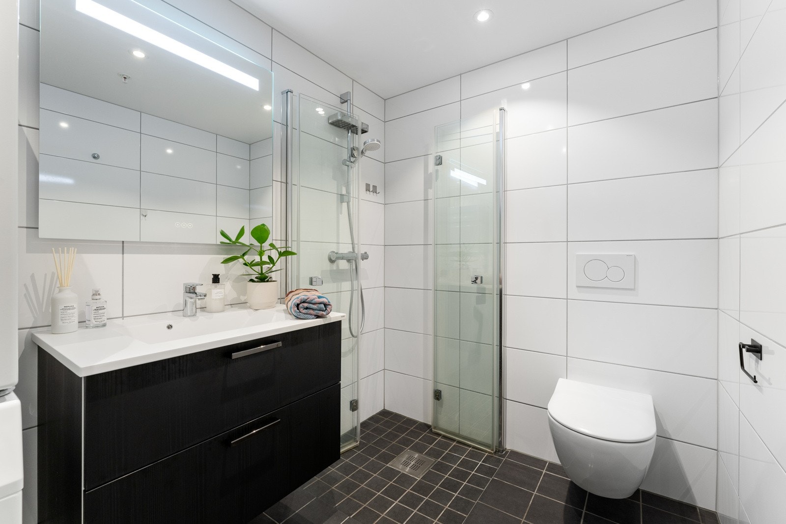 Badet er pent og helfliset. Her er det innredet med dusjnisje, toalett og heldekkende servant med belyst speil over. Galleribilde