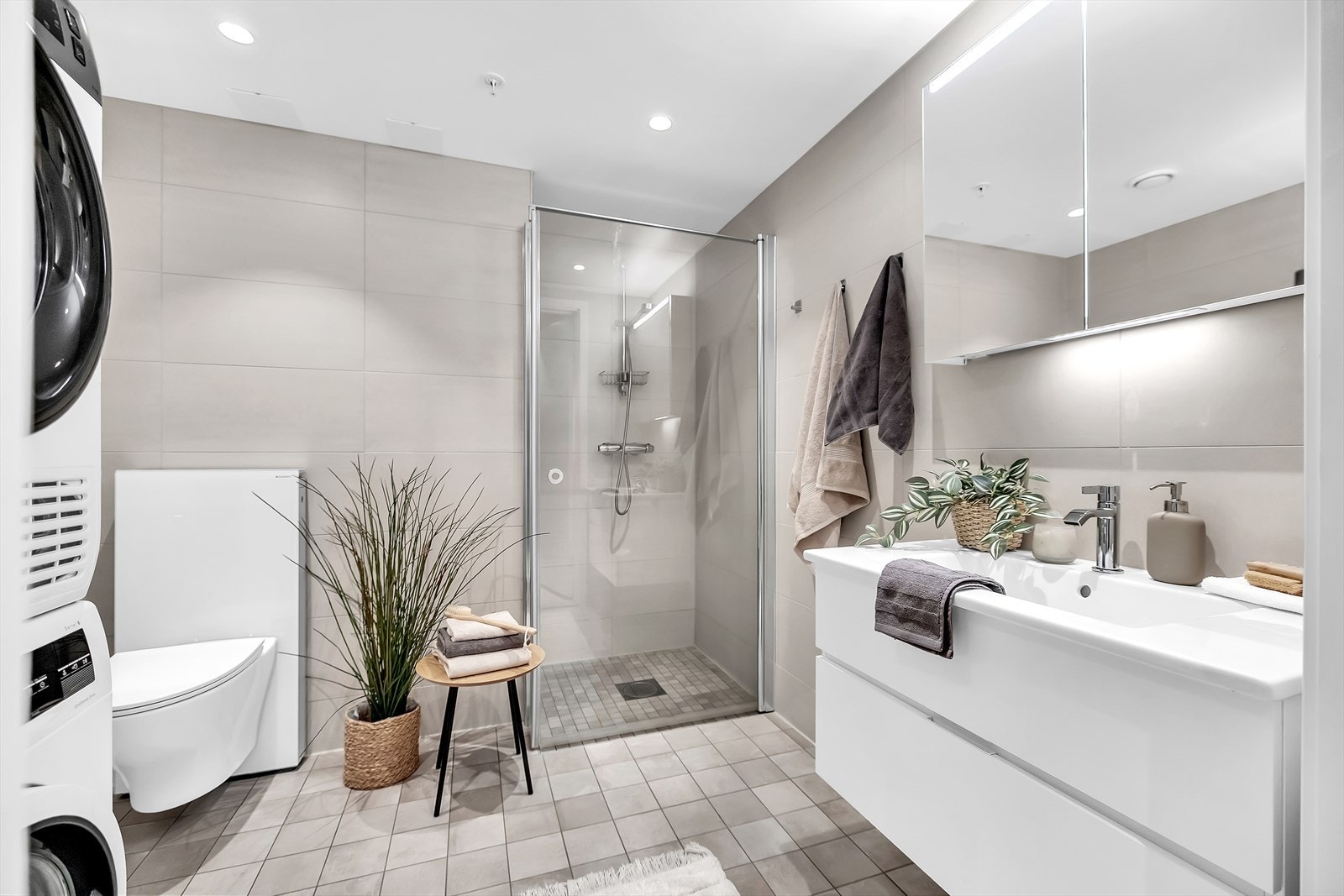 Delikat og romslig bad med dusjhjørne, vegghengt wc, servant med skuffer og speilskap. Galleribilde