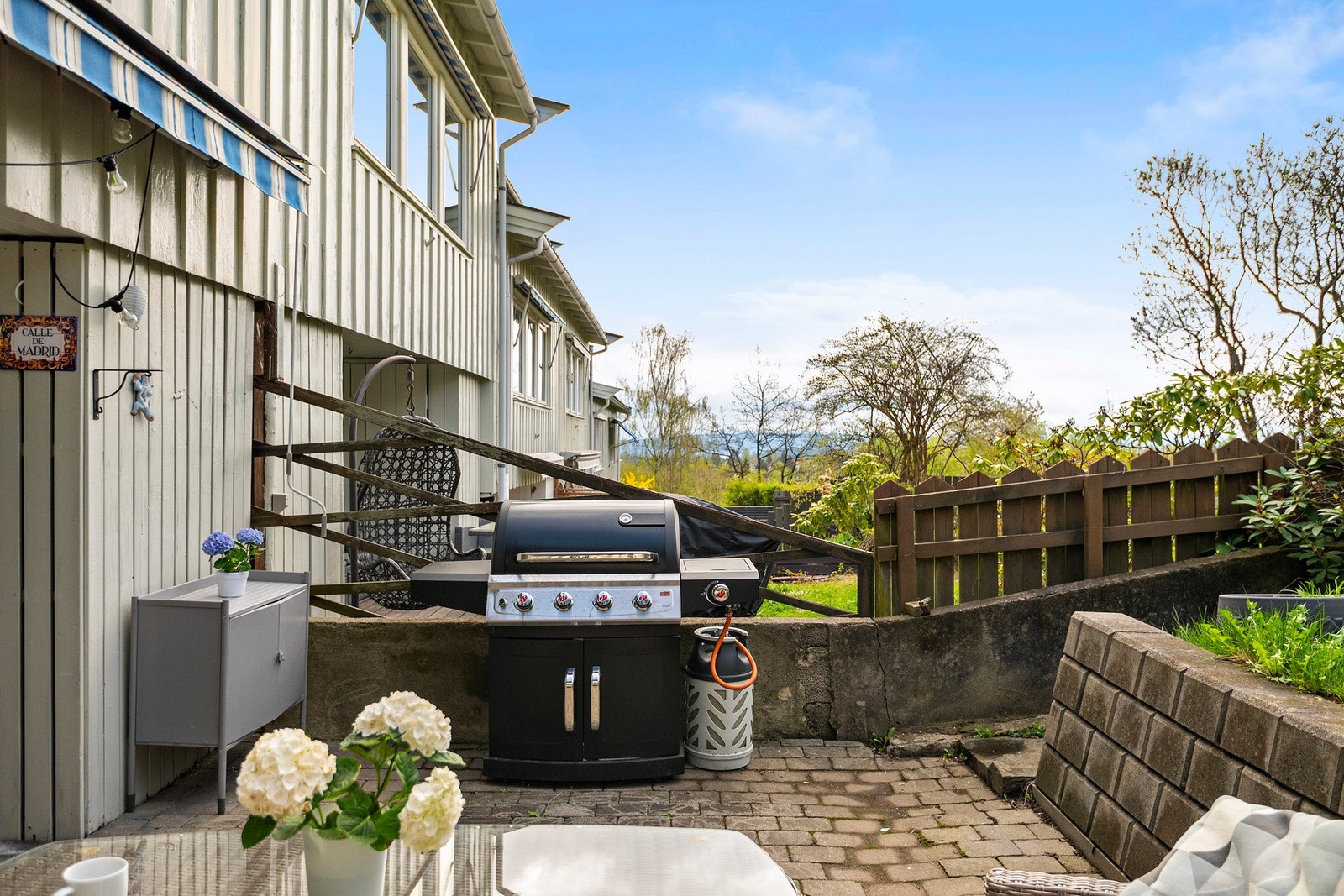 Terrassen er lagt med belegningsstein og har videre adkomst til en skrånet hage med gress Galleribilde