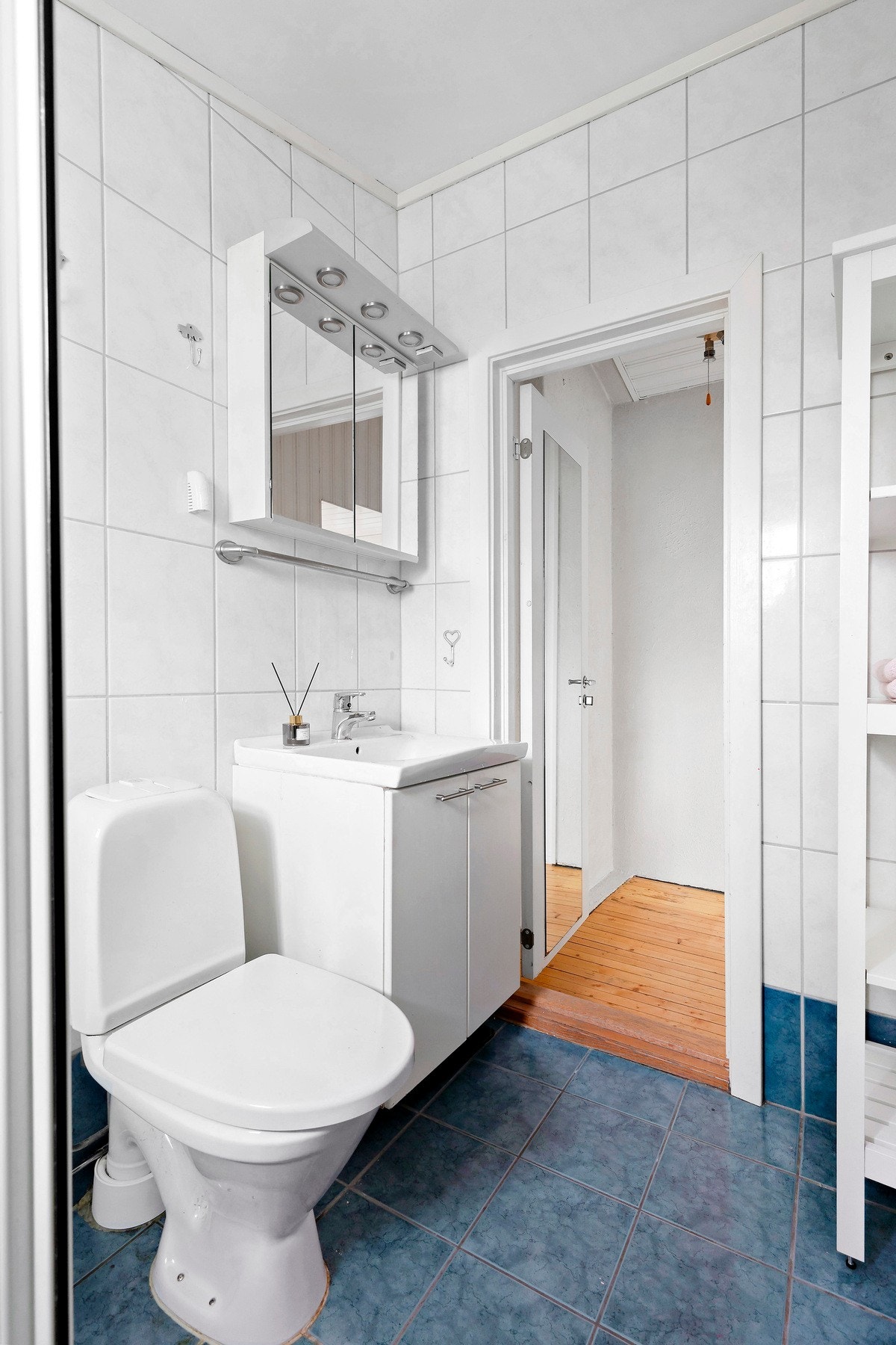 Rommet er innredet med vegghengt servantinnredning med skap, vegghengt speilskap med lys, gulvstående toalett og dusj på gulv med glassdører og vegghengt dusjarmatur Galleribilde