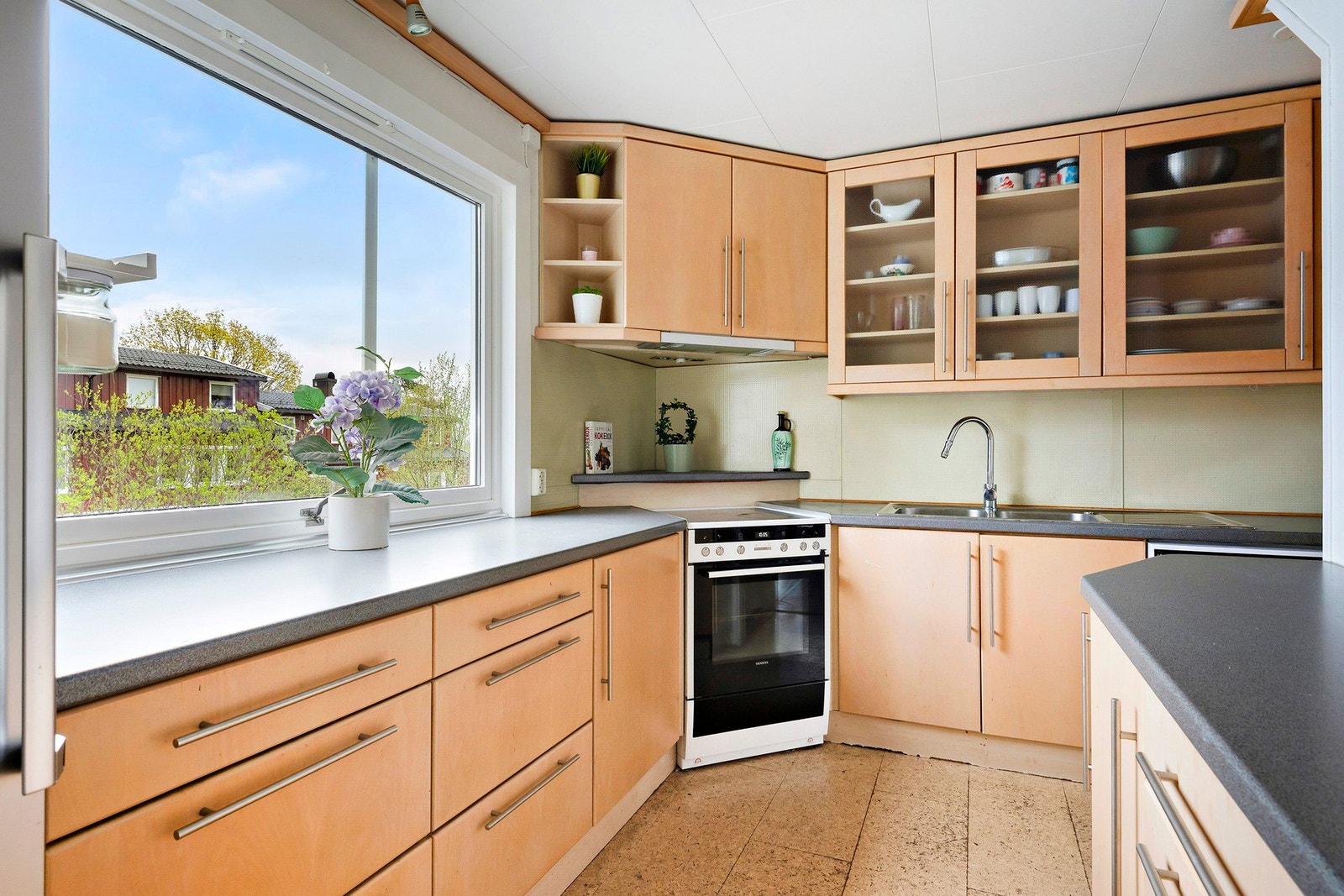Boligen har et stort kjøkken fra 2004 med glatte fronter og laminat benkeplate, enkelte glassfronter på overskap Galleribilde