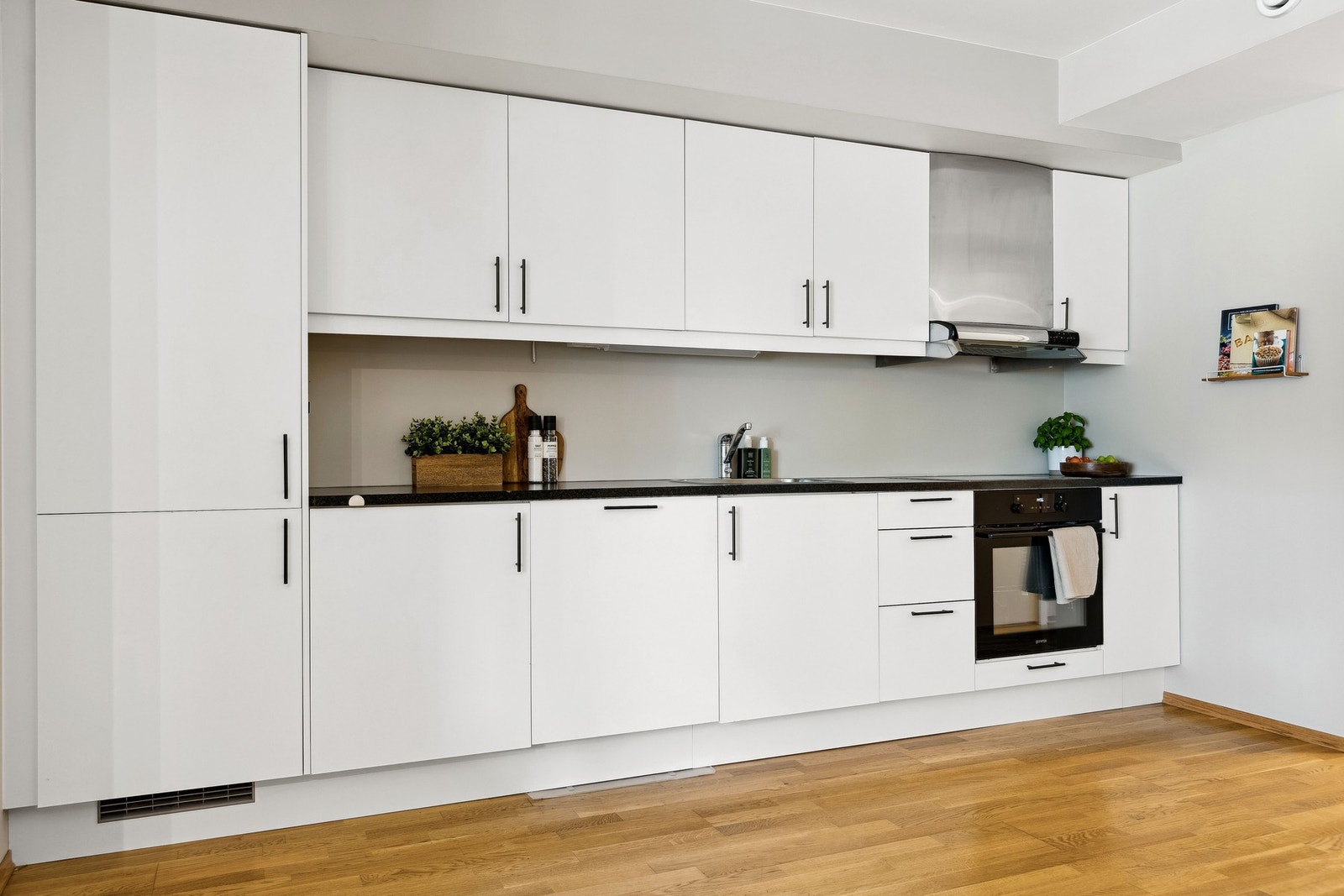 Arealeffektivt kjøkken med glatte fronter og mørk benkeplate. Galleribilde