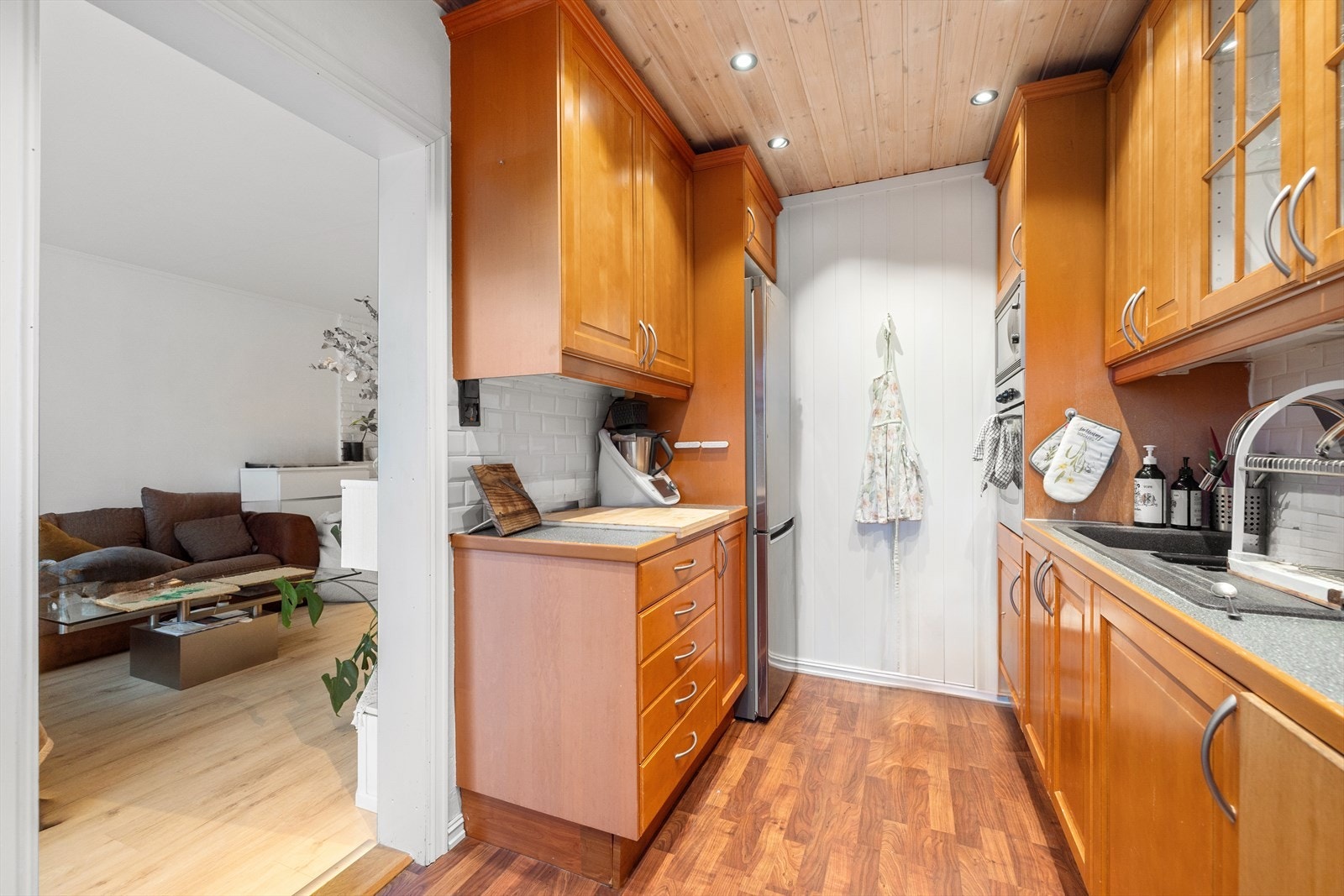 Kjøkkeninnredningen består av profilerte fronter, laminert benkeplate, downlights, frittstående kombiskap, oppvaskkum, og er utstyrt med integrerte hvitevarer som stekeovn, mikrobølgeovn, oppvaskmaskin og induksjonstopp. Galleribilde