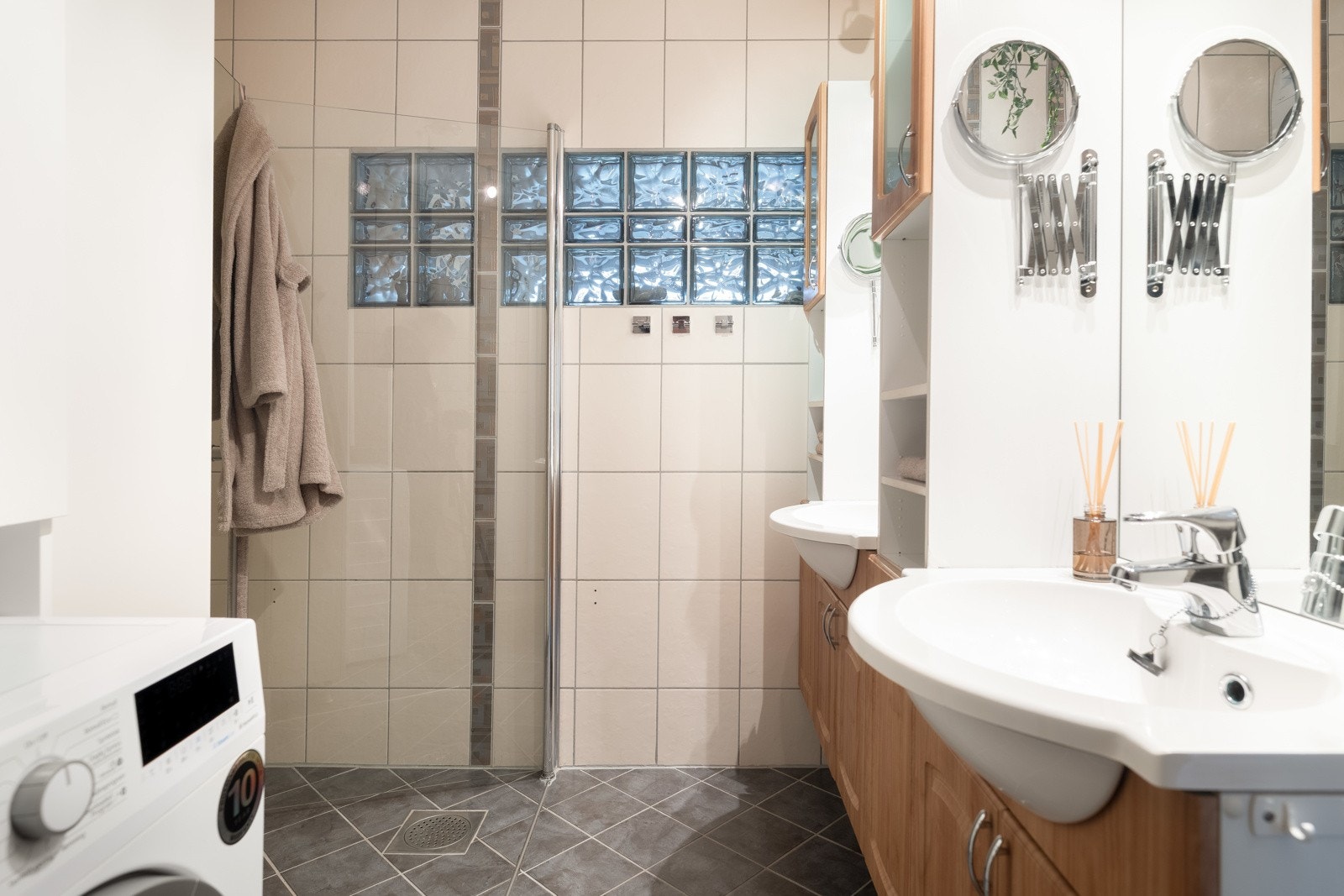 Baderommet er flislagt og utstyrt med dobbeltservant, dusjhjørne med foldbare dusjdører og opplegg for vaskemaskin. Galleribilde