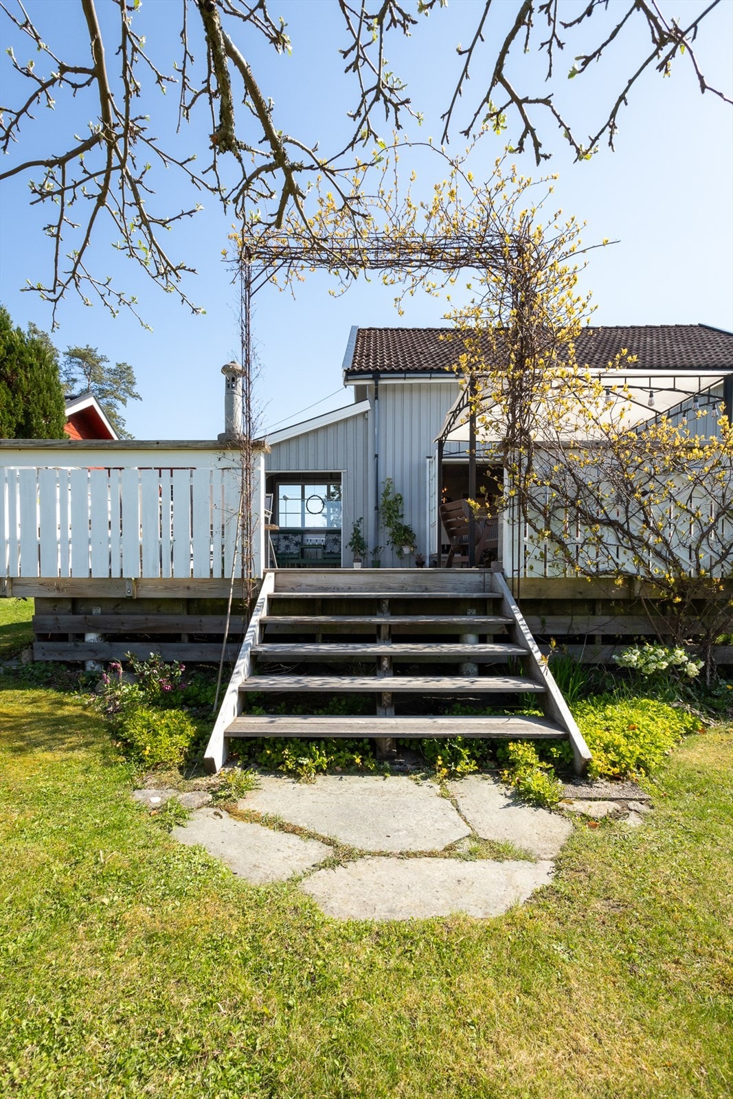 Fra verandaen er det direkte adkomst til den flotte hagen, hvor du kan nyte friluftslivet og enkelt bevege deg mellom uteplassen og de frodige uteområdene. Galleribilde