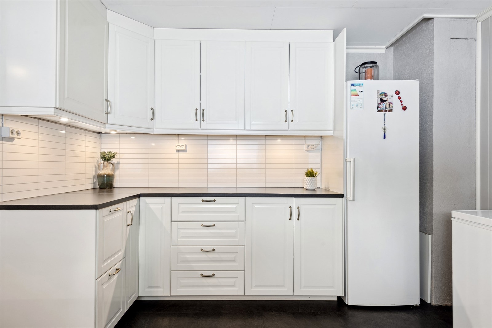 Kjøkkeninnredning med laminerte skrog,
profilerte fronter og laminert benkeplate med kjøkkenkum. Galleribilde