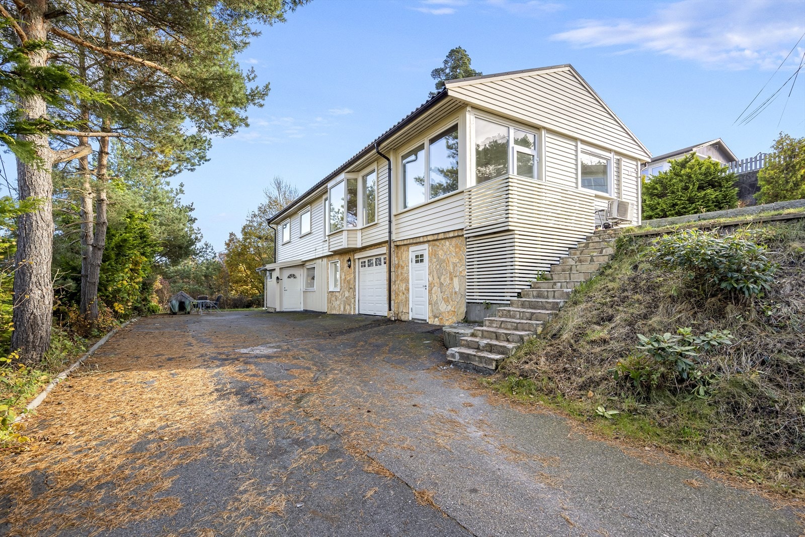 Tomten er planert over 2 nivåer hvor både øvre og nedre plan har asfaltert gårdstun med rikelig med parkering. Galleribilde