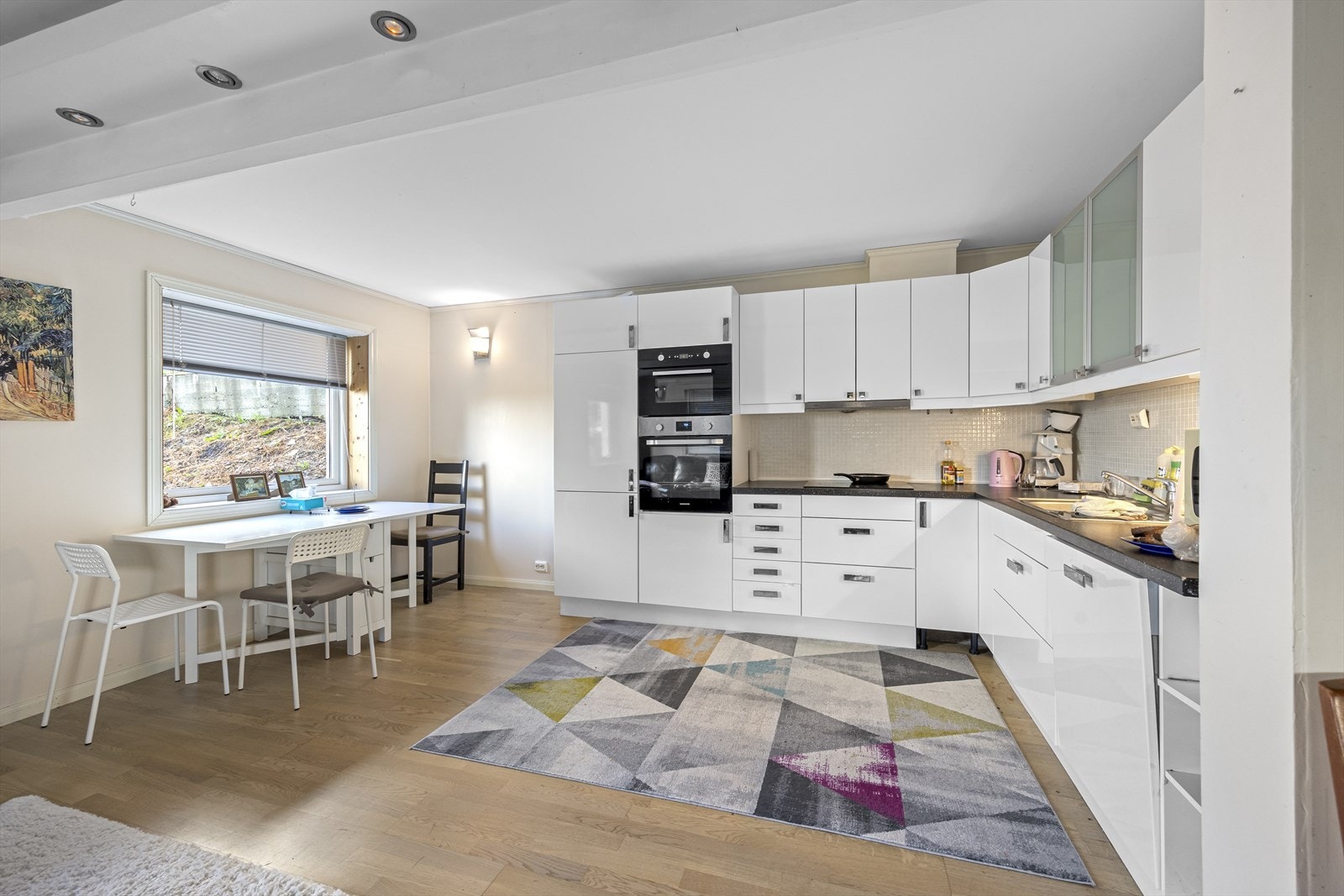 Kjøkken i underetasjen. Kjøkkenet har innredning i hvit, høyglans utførelse med integrert komfyr, induksjonstopp, mikro og oppvaskmaskin. Galleribilde