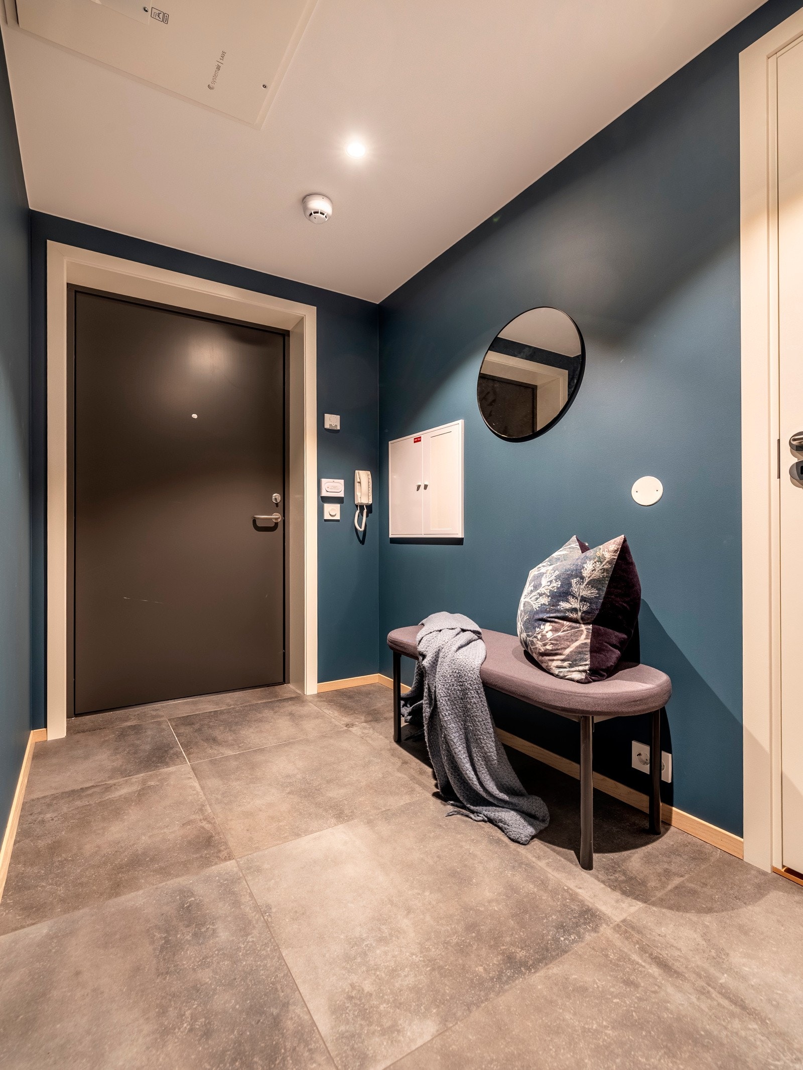 Allerede ved inngangsdøren blir du møtt av et stilfullt design med vegger malt i en dyp blåfarge og gulv dekket med store fliser i grå nyanser. Galleribilde