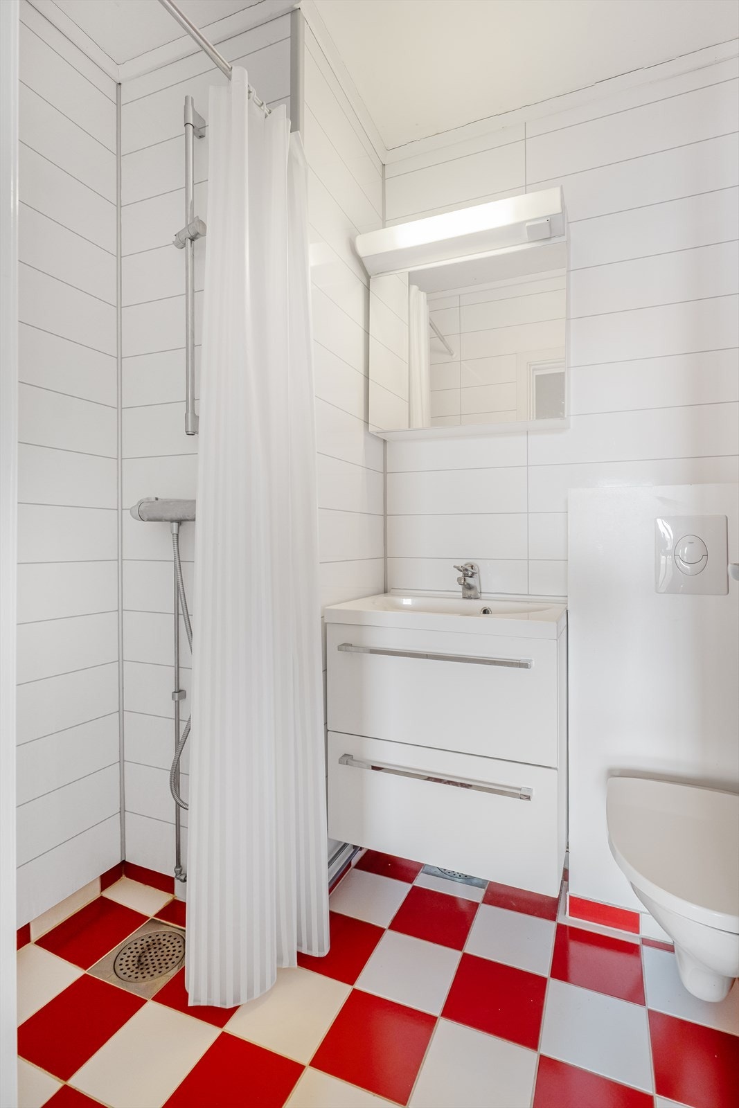 Pent og stilrent bad fra 2012 med varmekabler i gulv. Det er våtromsplater på vegger og fliser på gulv. Badet er innredet med veggmontert wc, dusj og servant i innredning med skuffer samt speil med lys i rommet. Galleribilde