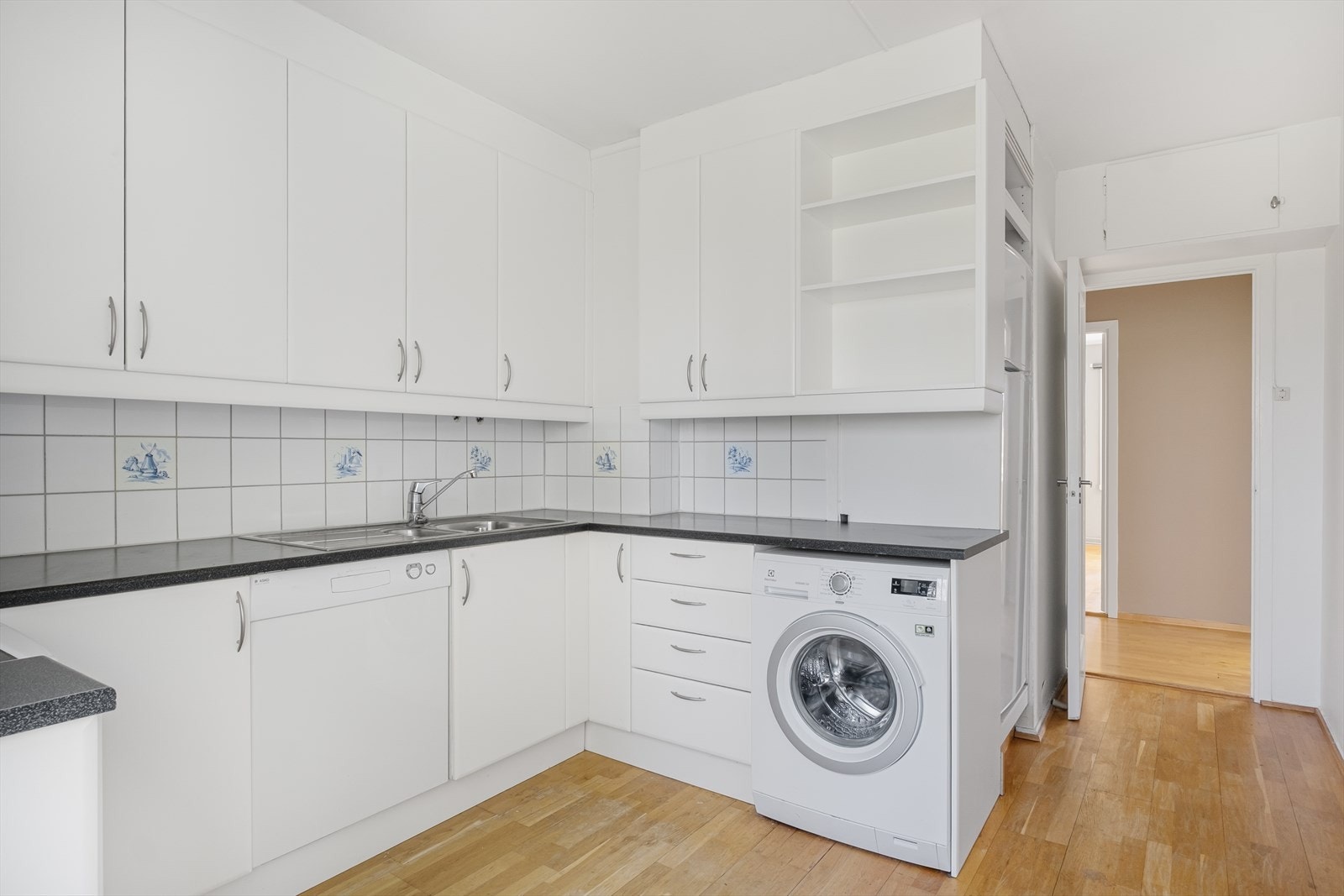 Kjøkkeninnredning med laminerte benkeplater, slette fronter, flislagt backsplash og ventilator med utkast til friluft. Kjøleskap, komfyr, oppvaskmaskin og vaskemaskin medfølger. Galleribilde