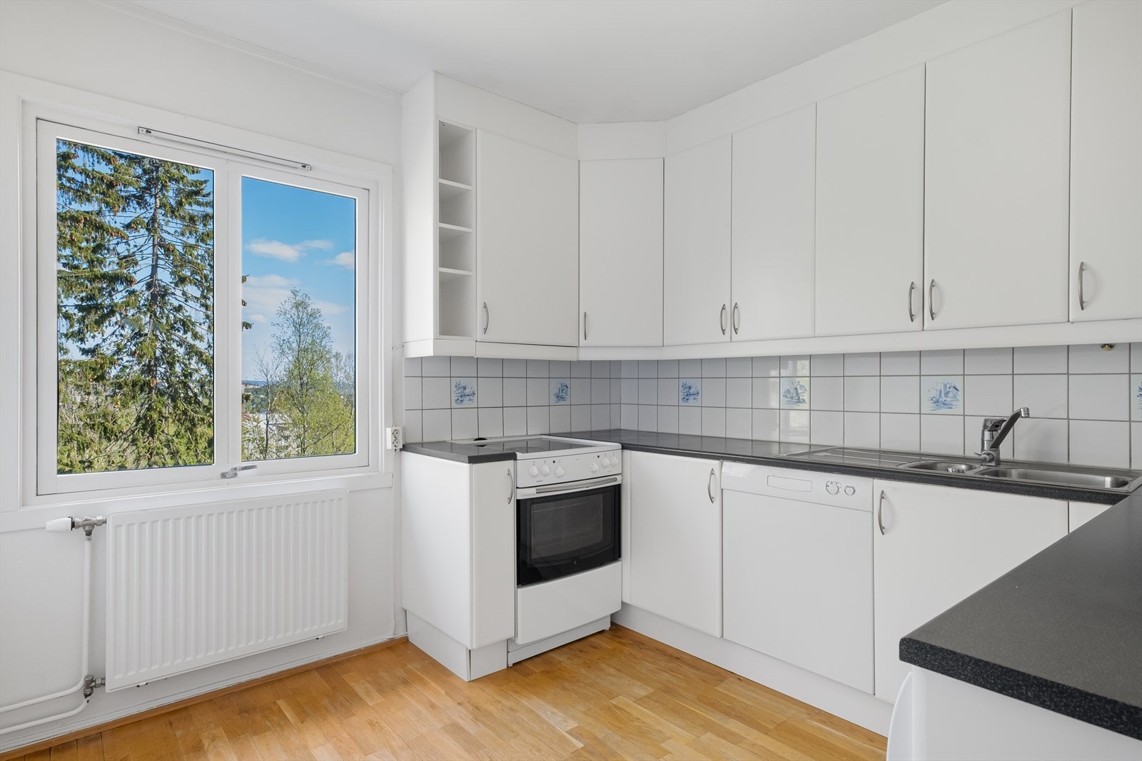 Lyst og innbydende kjøkken med plass til lite kjøkkenbord og stoler. Kjøkkenet er designet og innredet med tanke på funksjonalitet, og har godt med skap- og benkeplass. Galleribilde