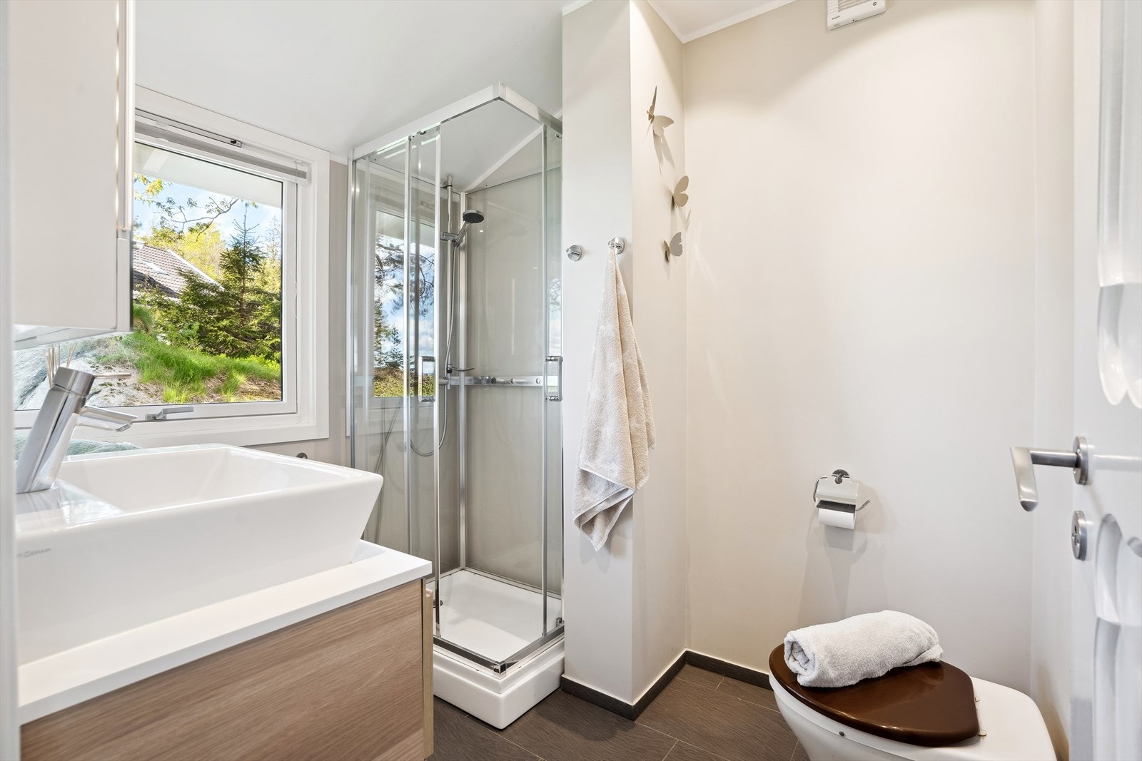 Baderom med varmekabler i flislagt gulv - badet er utstyrt med biodo, dusjkabinett og baderomsinnredning Galleribilde