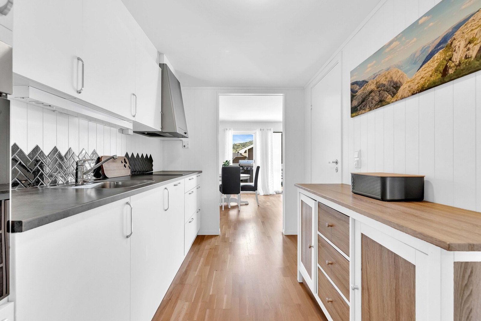 Kjøkkeninnredning fra Kvik med hvite glatte fronter og benkeplate i laminat med belysning under overskap. Galleribilde