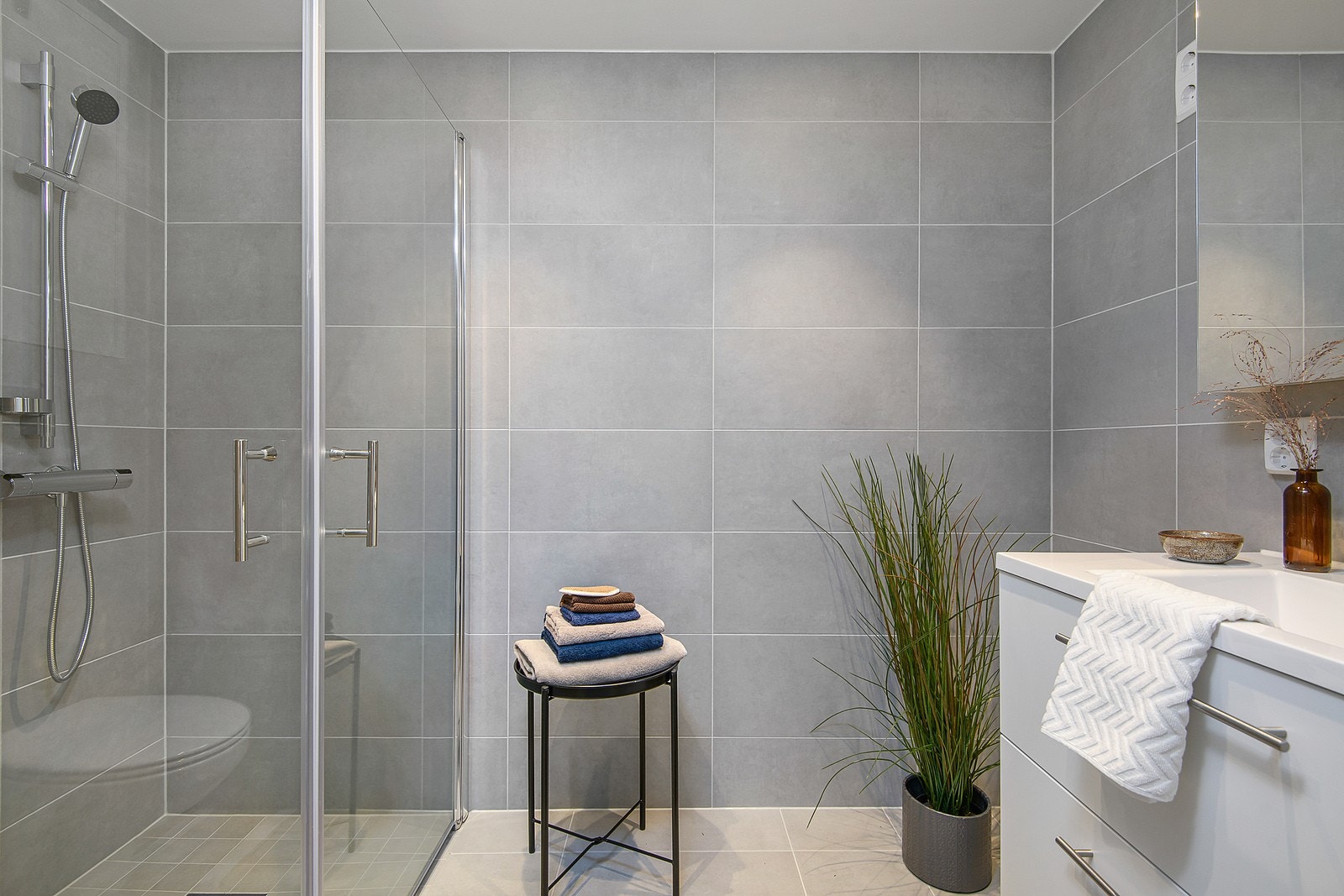 Flislagt bad med hvit baderomsinnredning. Galleribilde