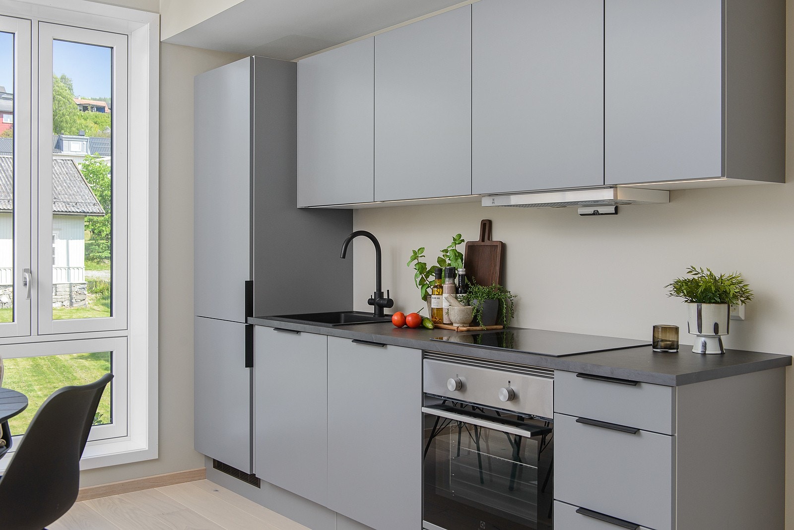 Moderne kjøkkeninnredning fra HTH med glatte fronter og integrerte hvitevarer som kombiskap, stekeovn, induksjonstopp og oppvaskmaskin. Galleribilde