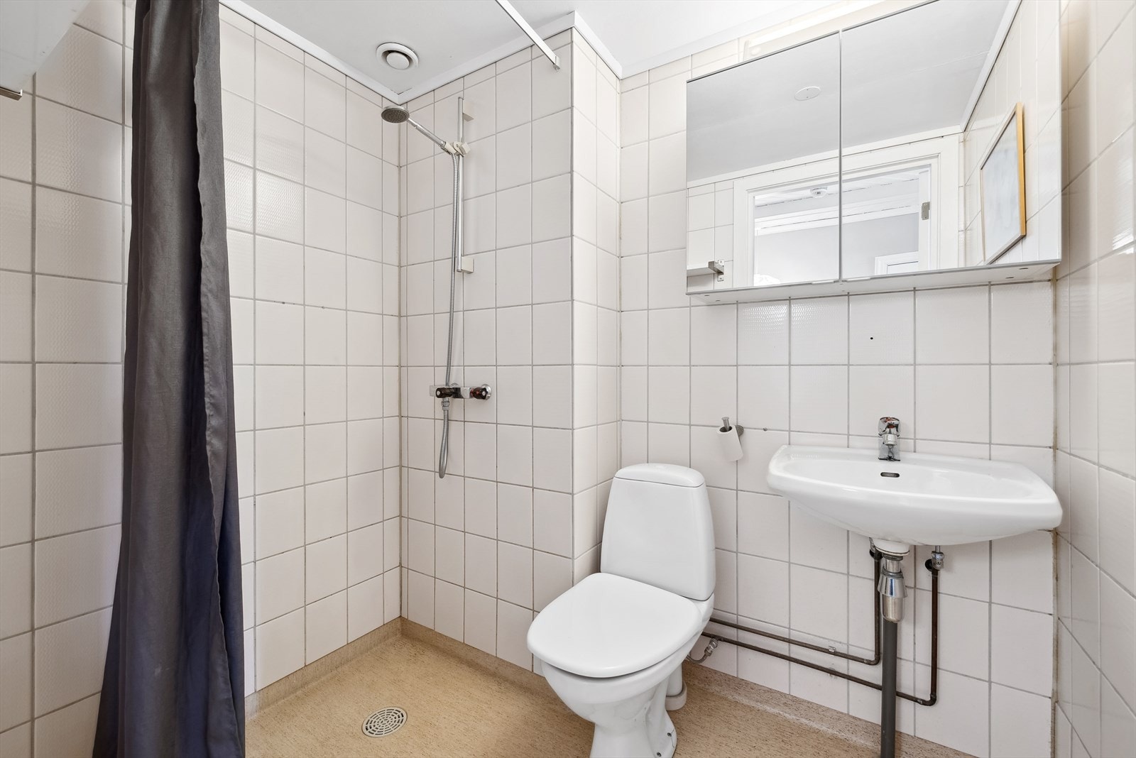 Leiligheten har et baderom med belegg på gulv og fliser på veggene. Galleribilde