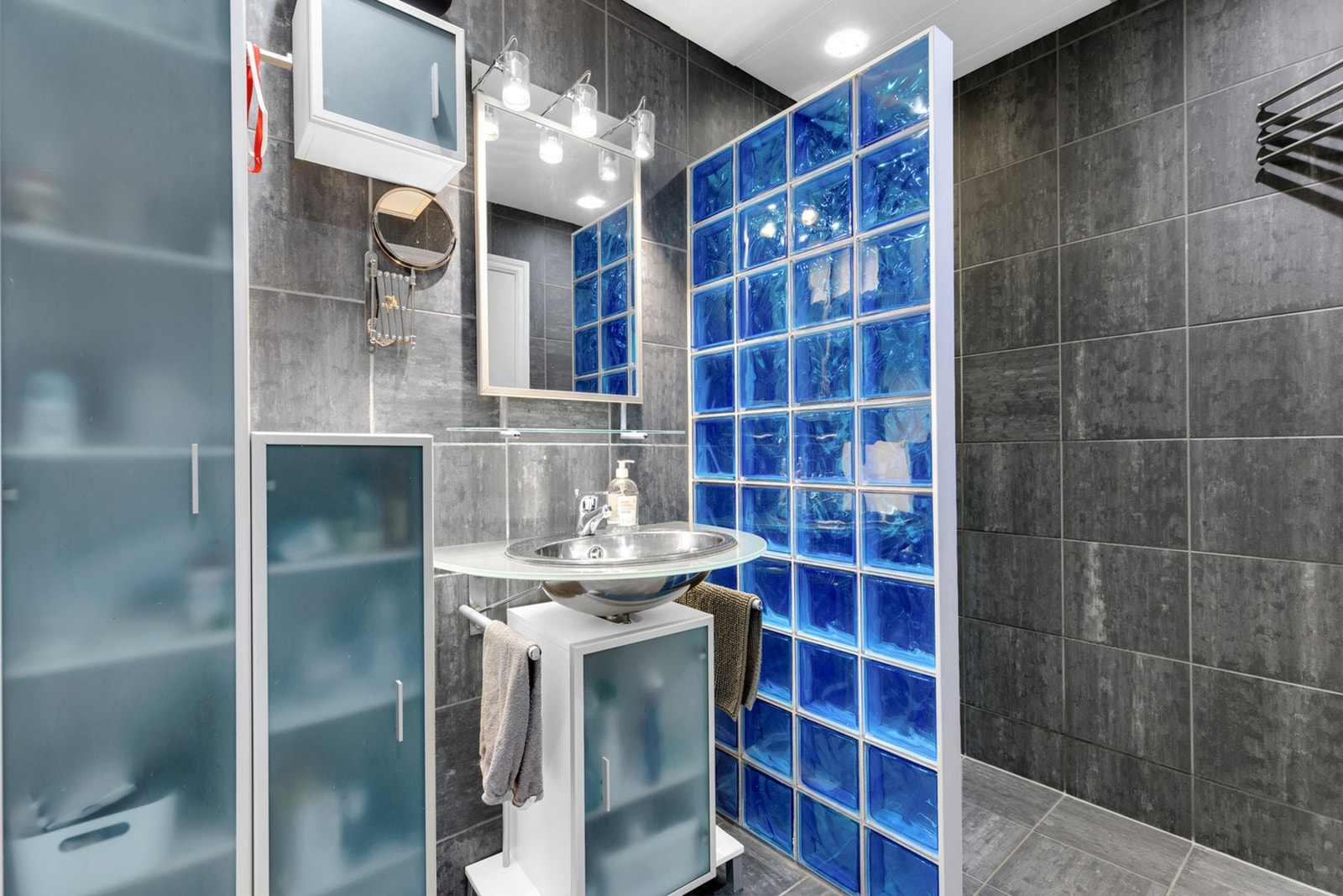 Flislagt baderom med mye skapplass og en romslig dusjnisje. Galleribilde